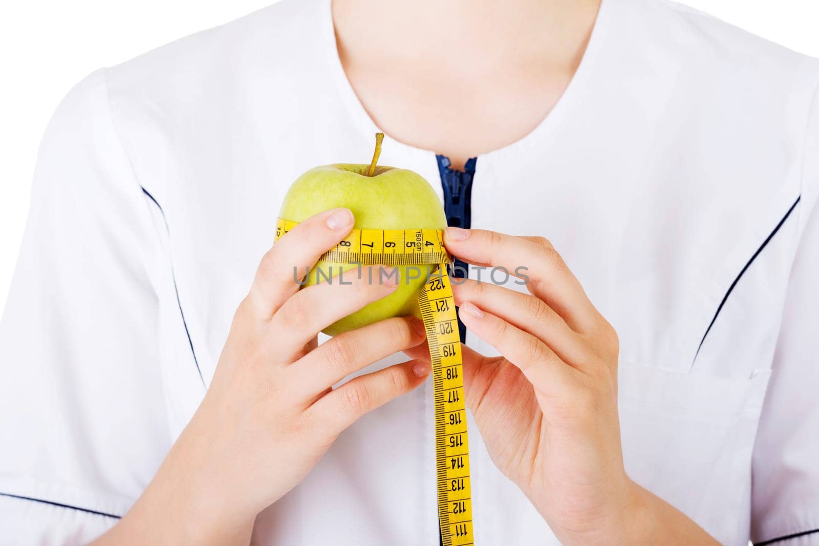 Healthy eating or diet concept. Smiling woman doctor with a green apple and measuring tape.