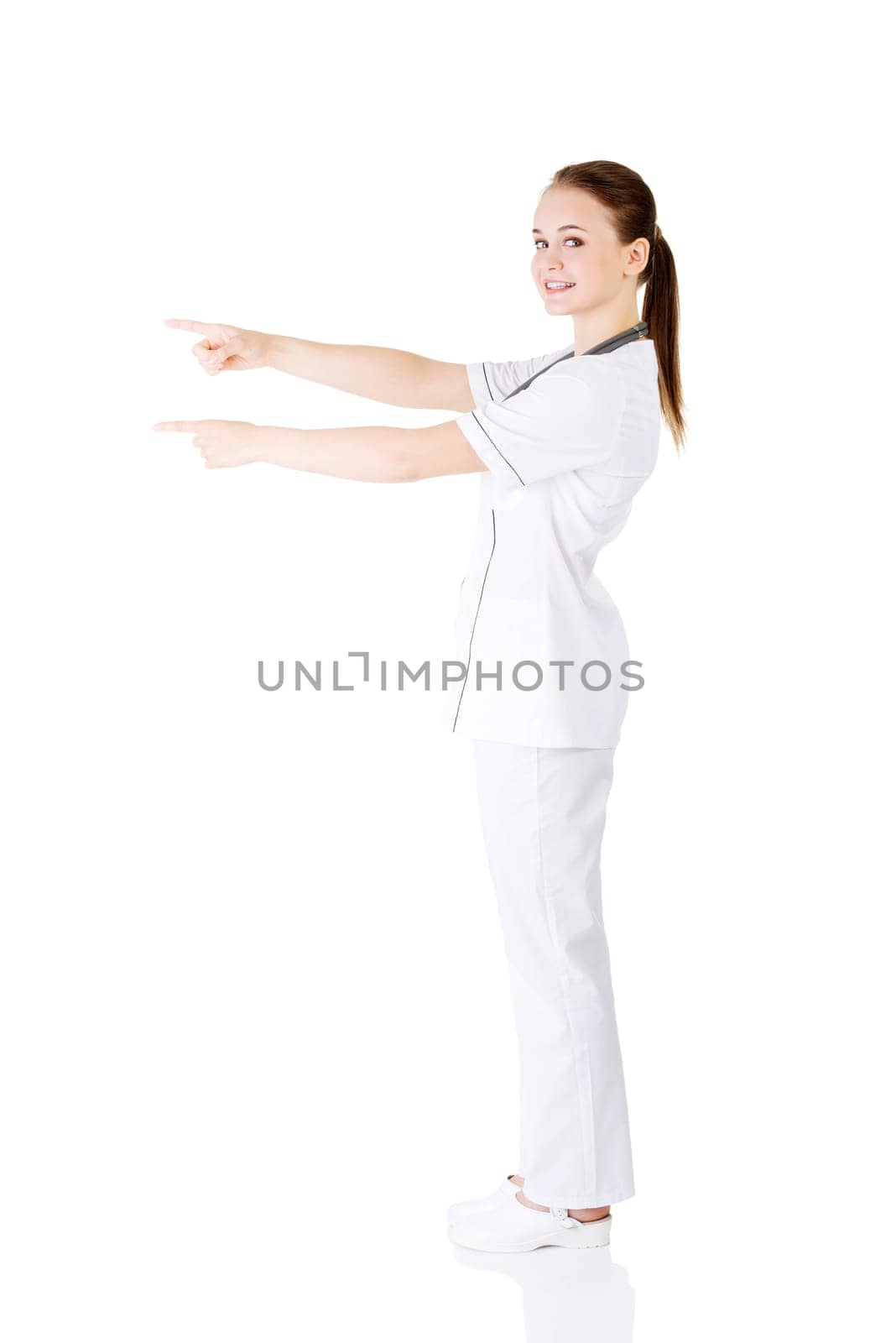 Woman doctor or nurse pointing on copy space. Isolated on white