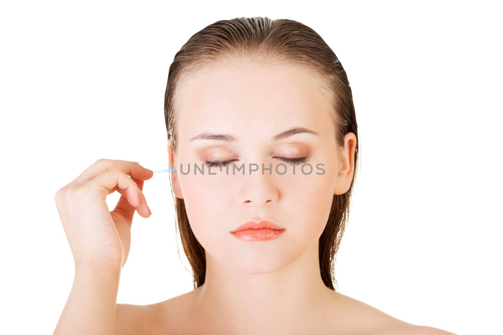 Woman face closeup while cleaning up an ear with a swab, over white.