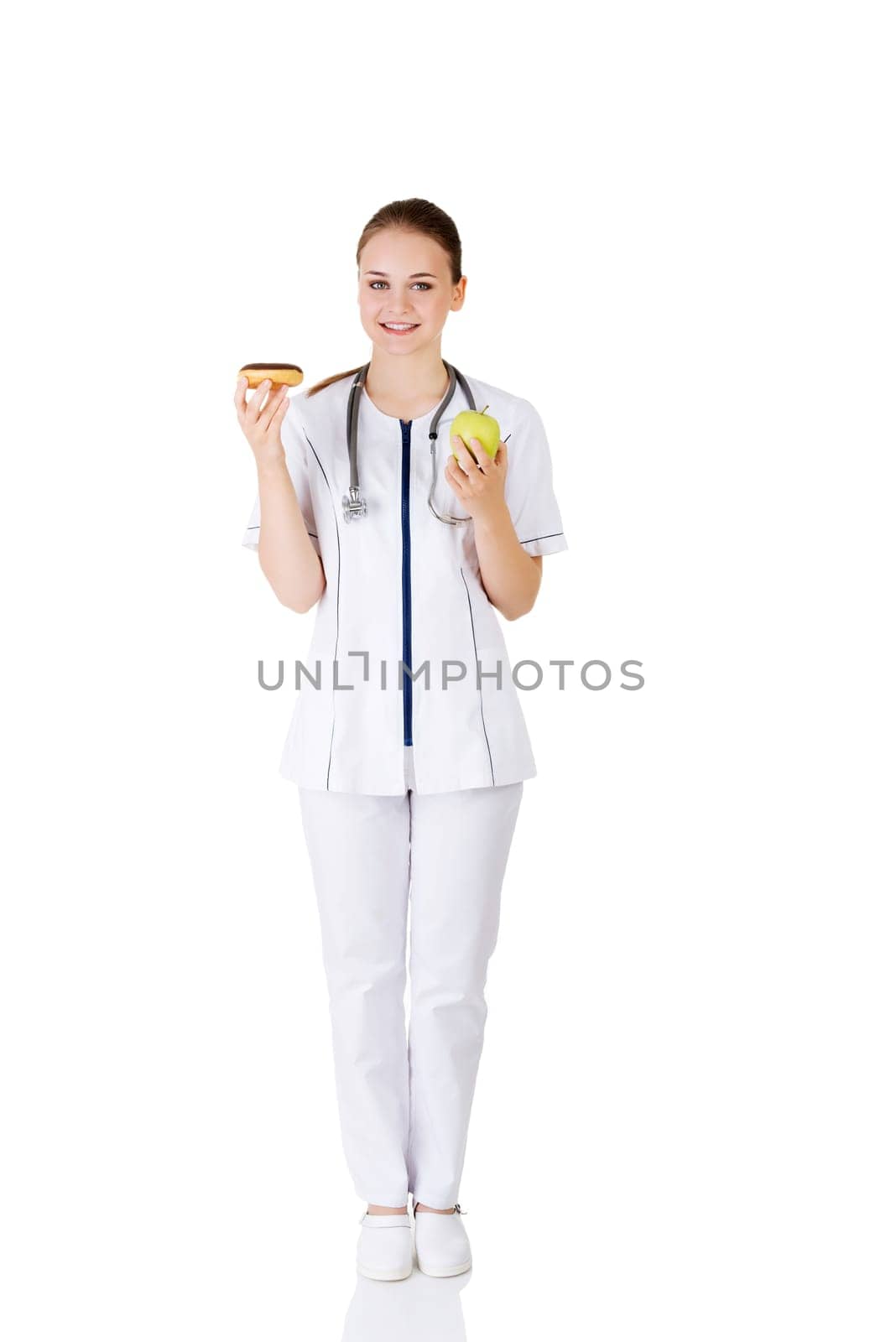 Dietician holding sweet doughnut and fresh healthy green apple. Isolated on white