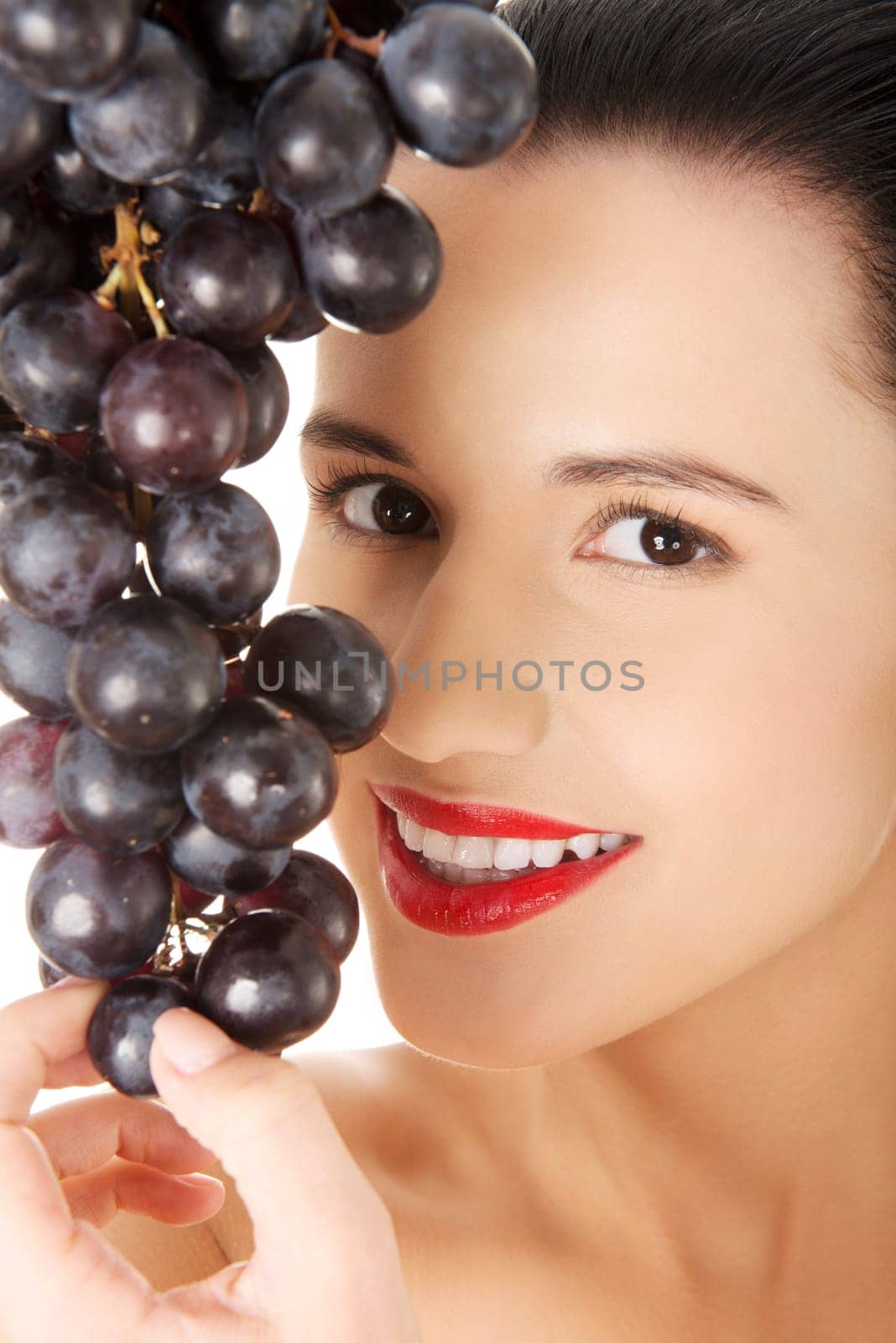 Beautiful sensual brunette eating grapes, isolated on white background