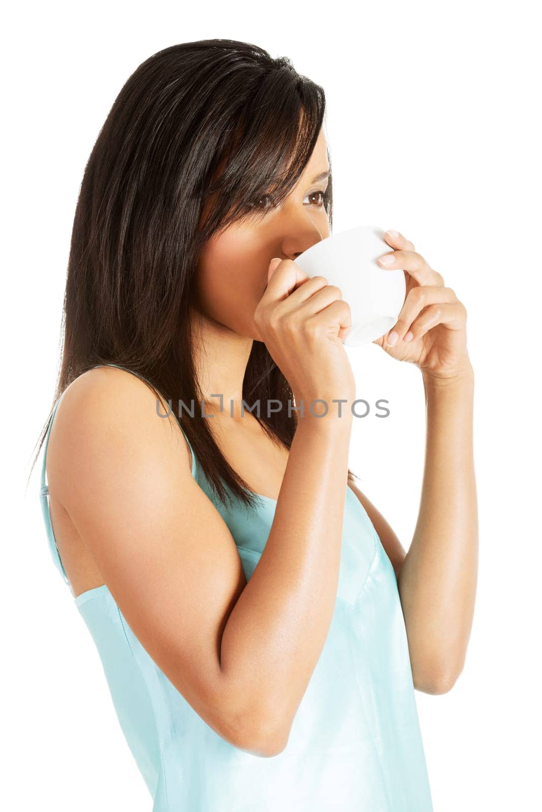 Attractive woman in nightwear drinking from cup, isoalted on white.