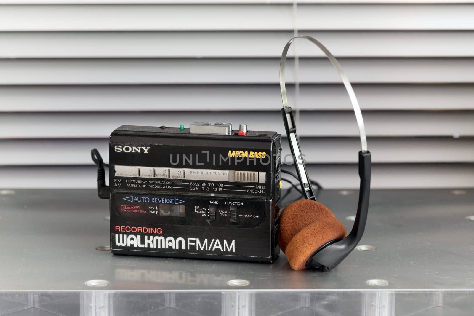 Vintage Walkman cassette player and stereo headphones on a metal table standing upright in close up in a music and entertainment concept