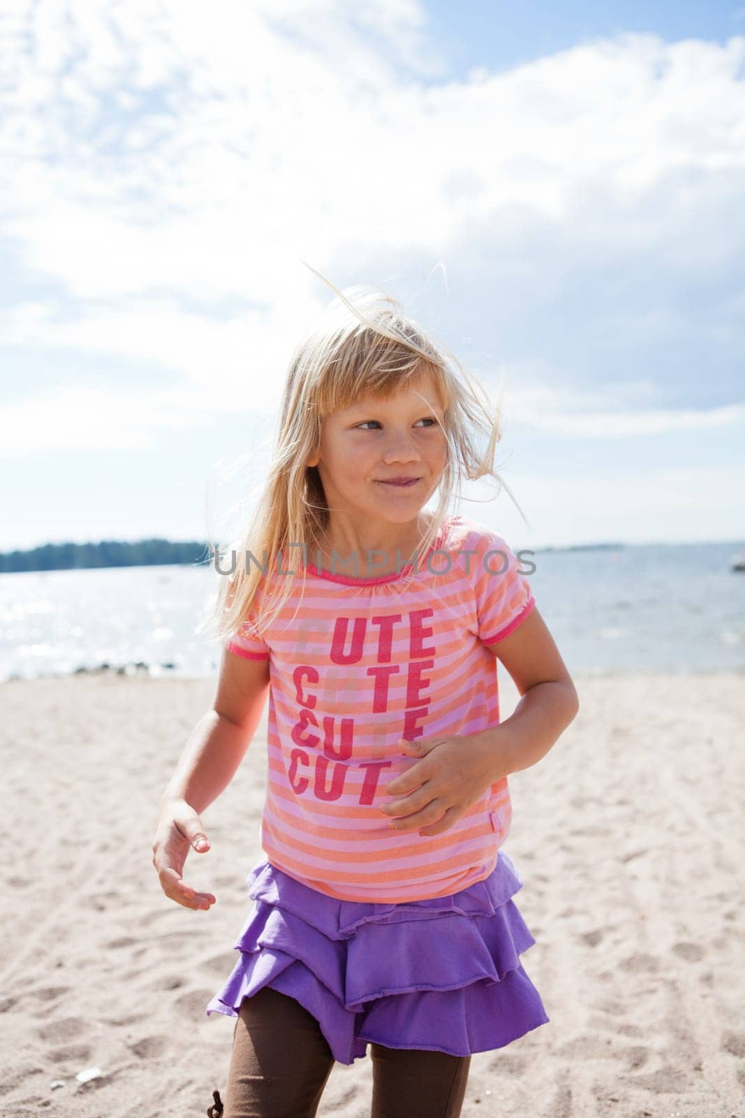 Cute happy young girl having fun at the beach in summer