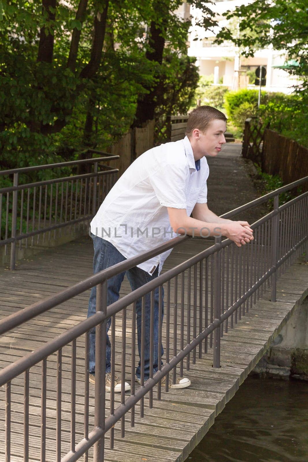 Young man stands on a bridge and thinks