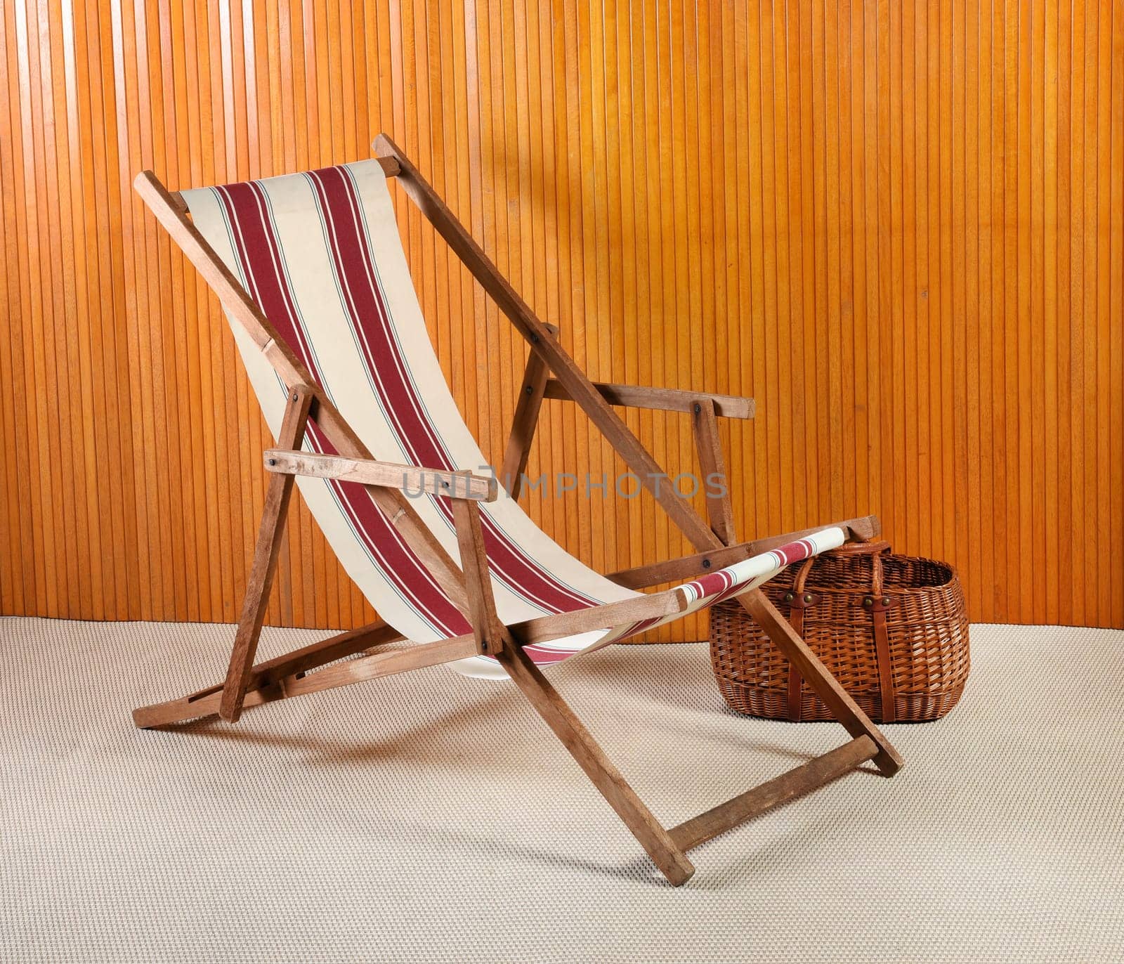 Side view of striped canvas deck chair and wicker basket in modern room