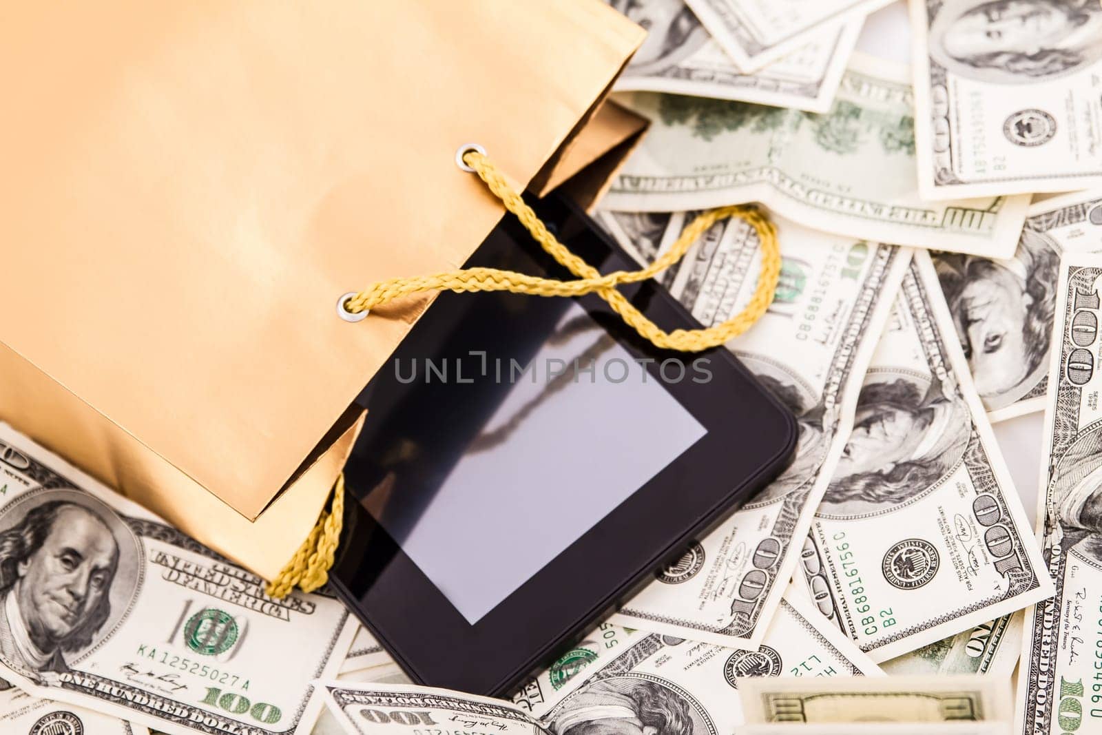 A gold gift bag with a Tablet PC and dollars isolated.