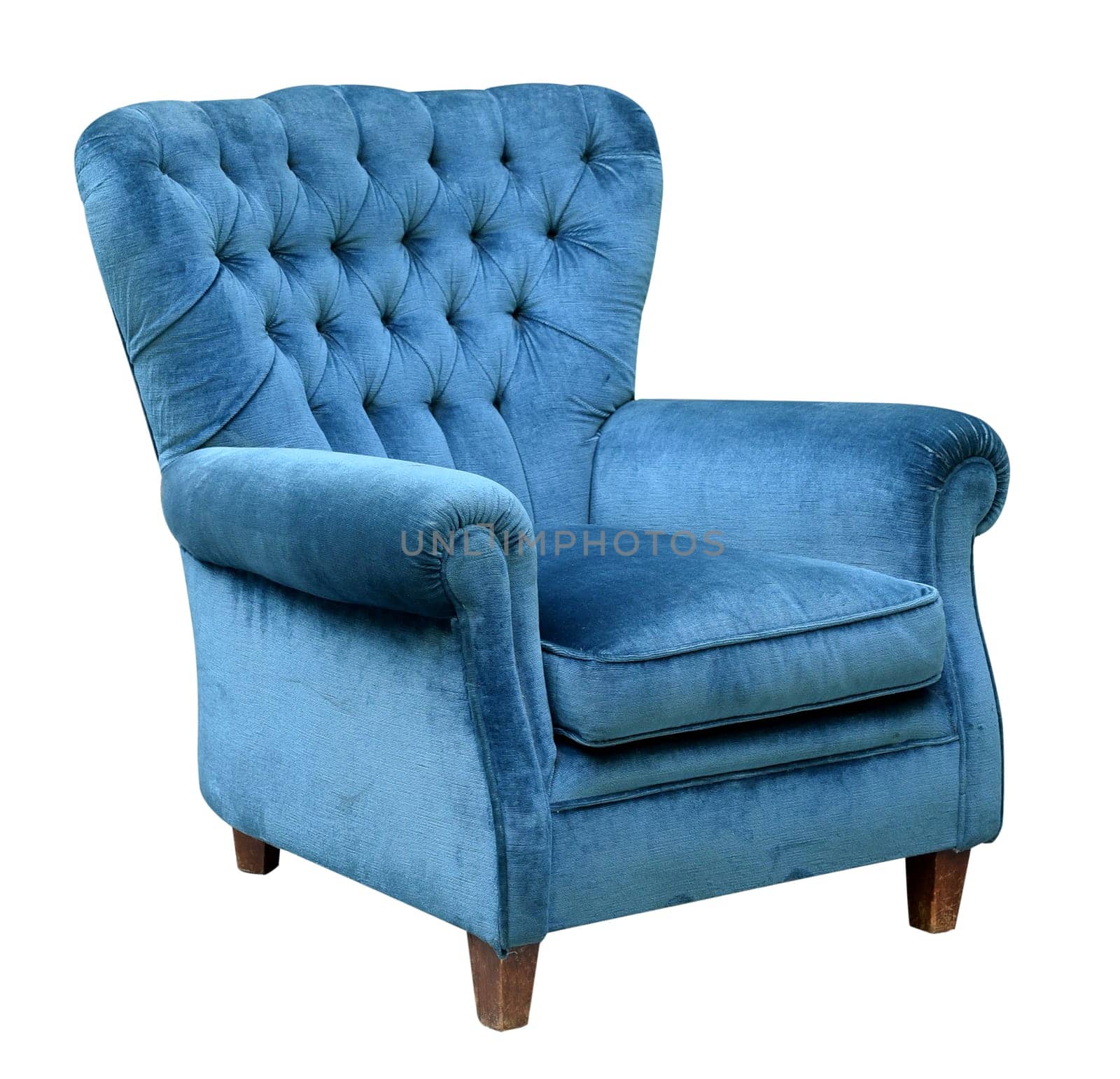 Upholstered blue velvet armchair with a retro high button back design isolated on white in a three quarter view
