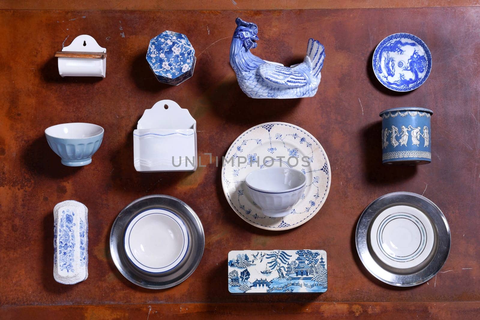 Collection of blue and white kitchen utensils or kitchenalia with plates, cup, canister, hen. bowl, and assorted containers in a neat arrangement