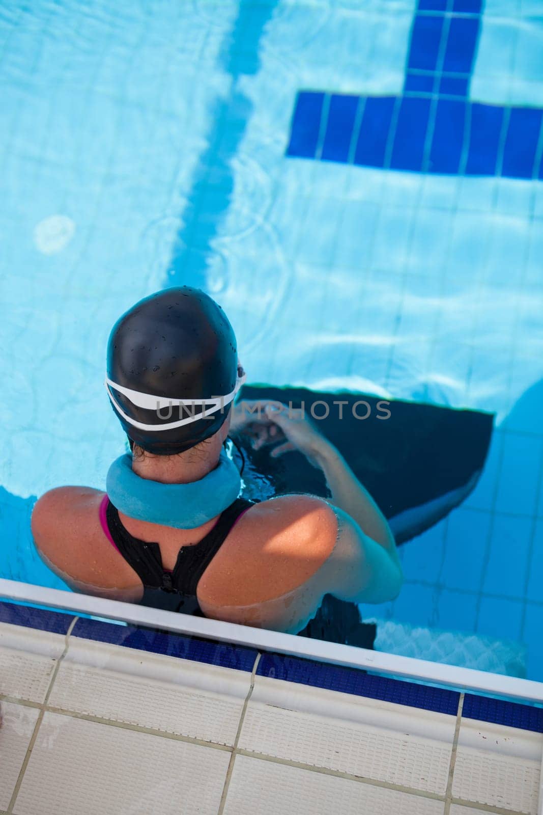 Female freediver with neck weight and monofin at edge of outdoor swimming pool