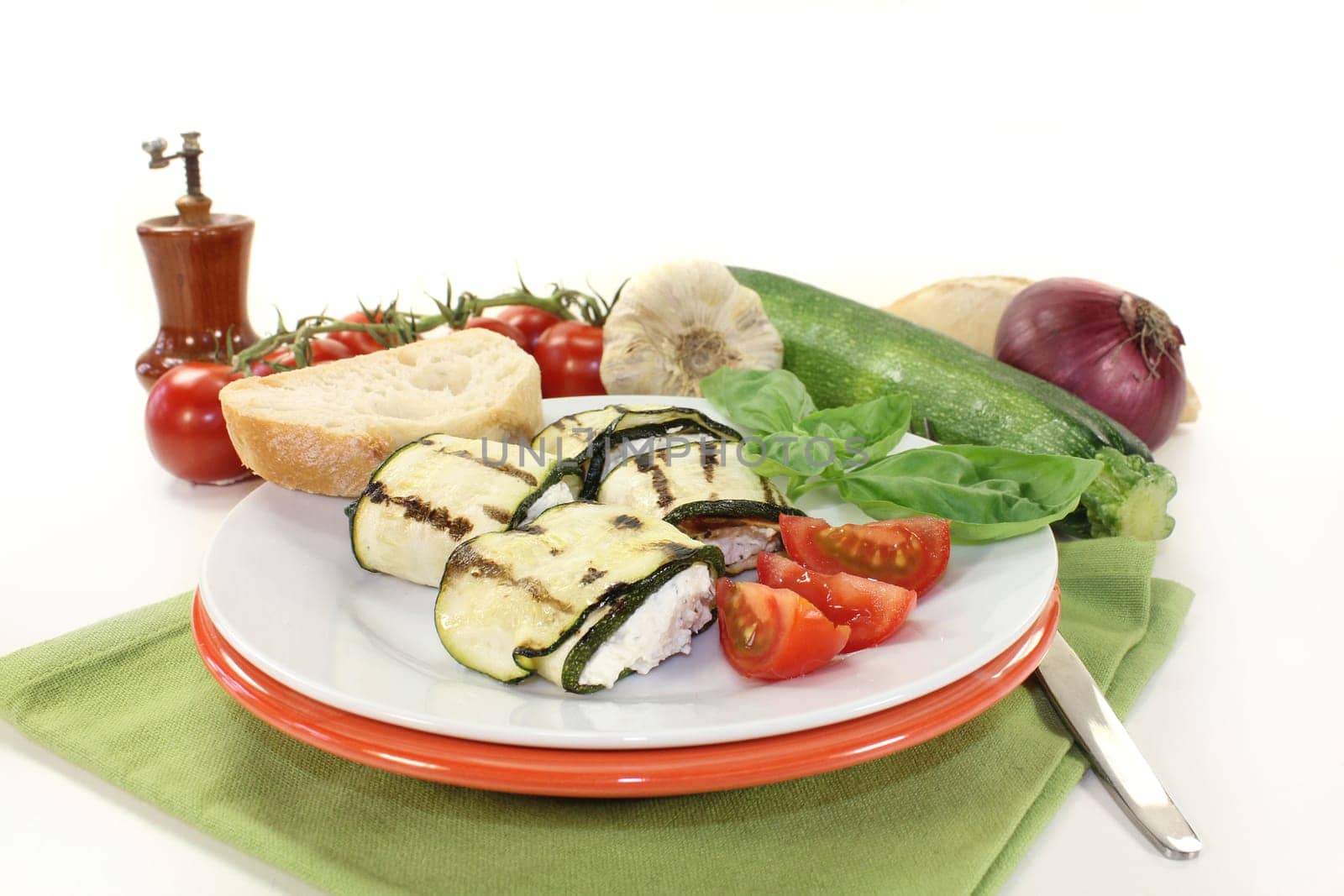 stuffed zucchini rolls and tomatoes on a white plate