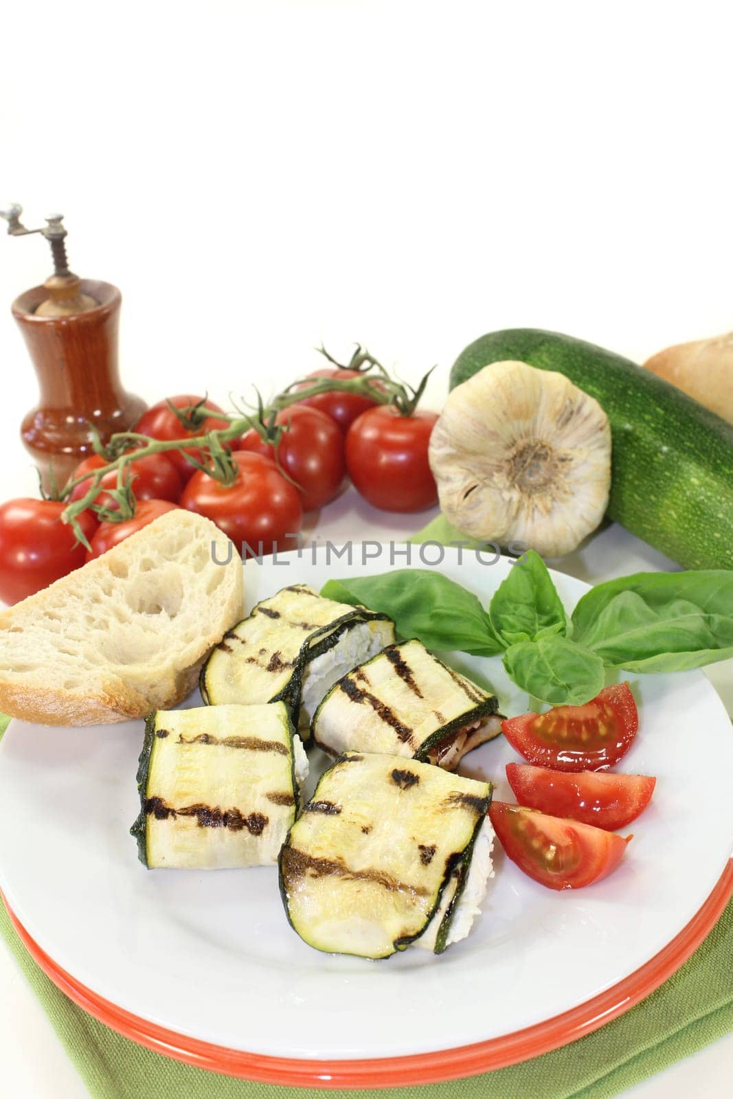 stuffed zucchini rolls and tomatoes on a white plate