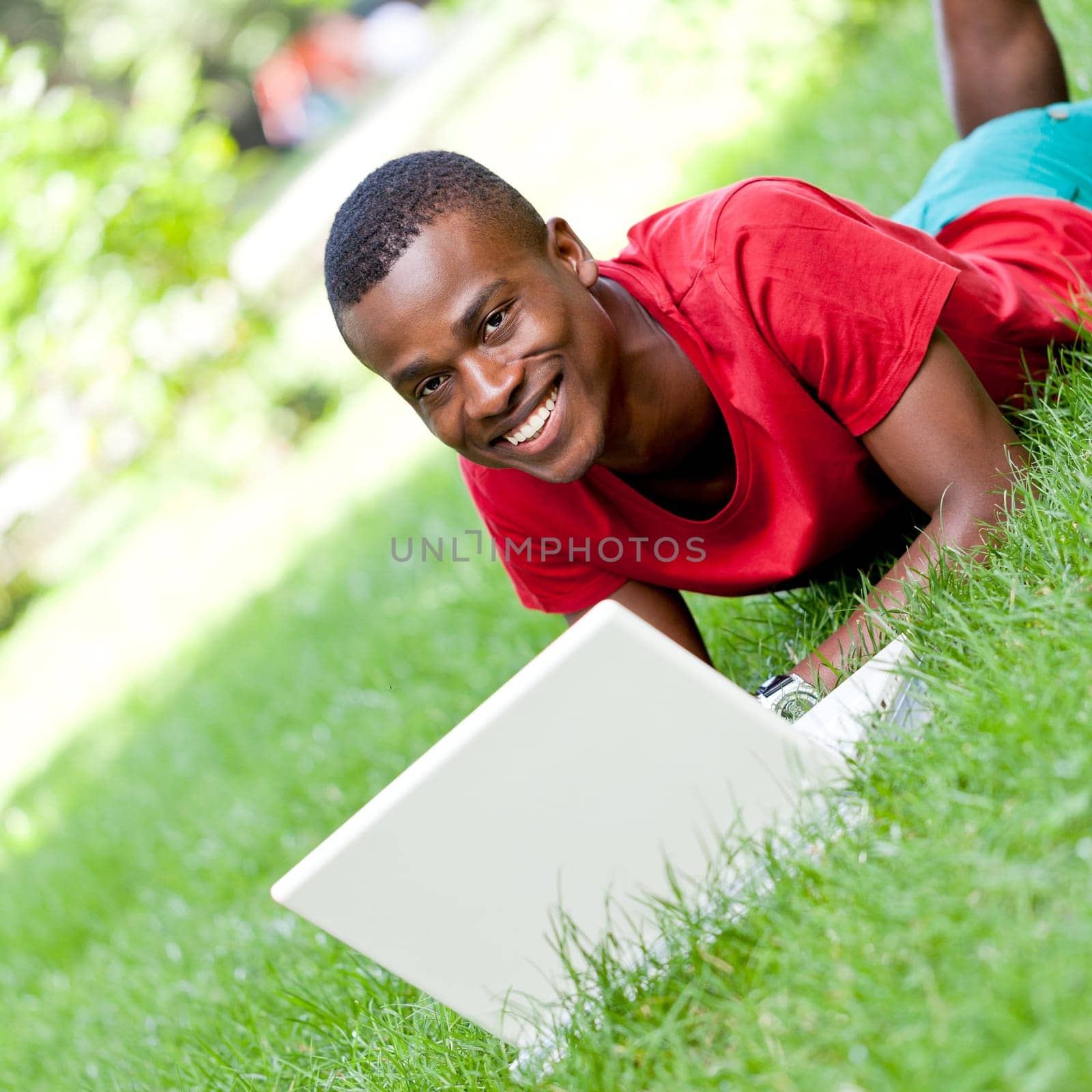 Young adult man student sitting in the meadow with notebook in the park Summer learning