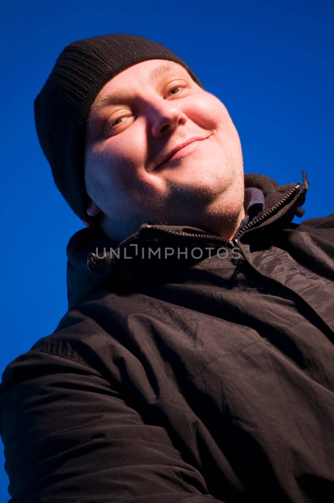 Upper body portrait of a middle-aged man in a black jacket in the evening against a blue sky in soffit