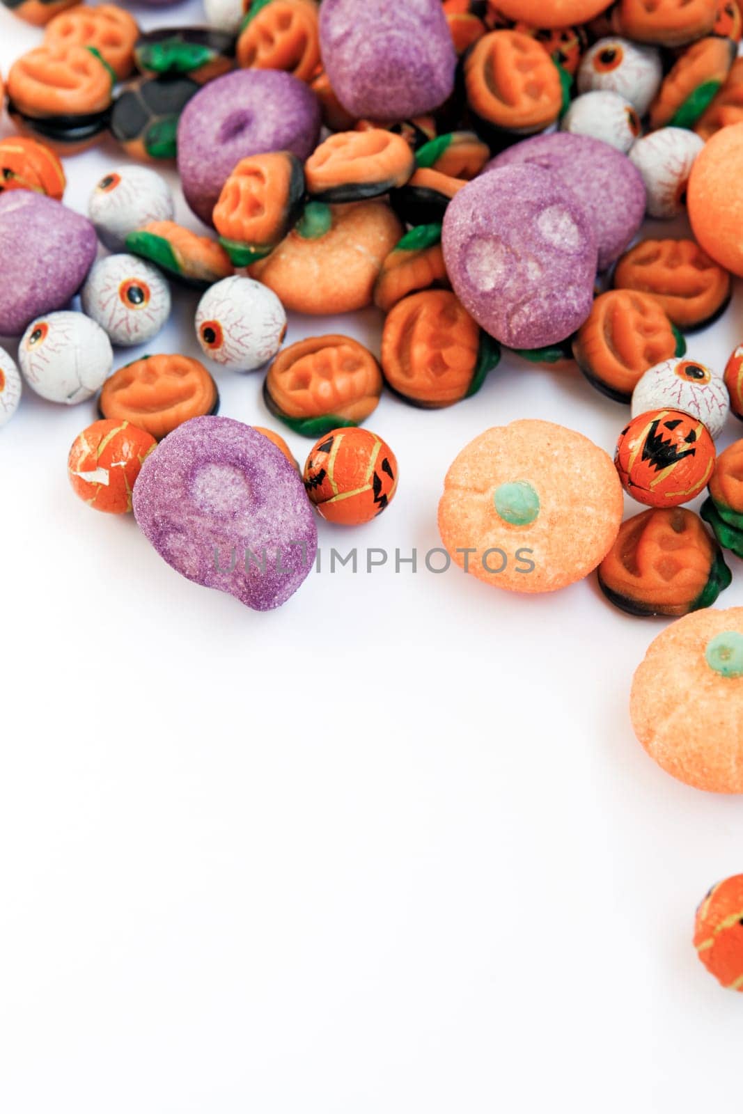 Colorful group of halloween candy in shape of pumpkins and skulls with funny, smiley faces. Large space for copy.