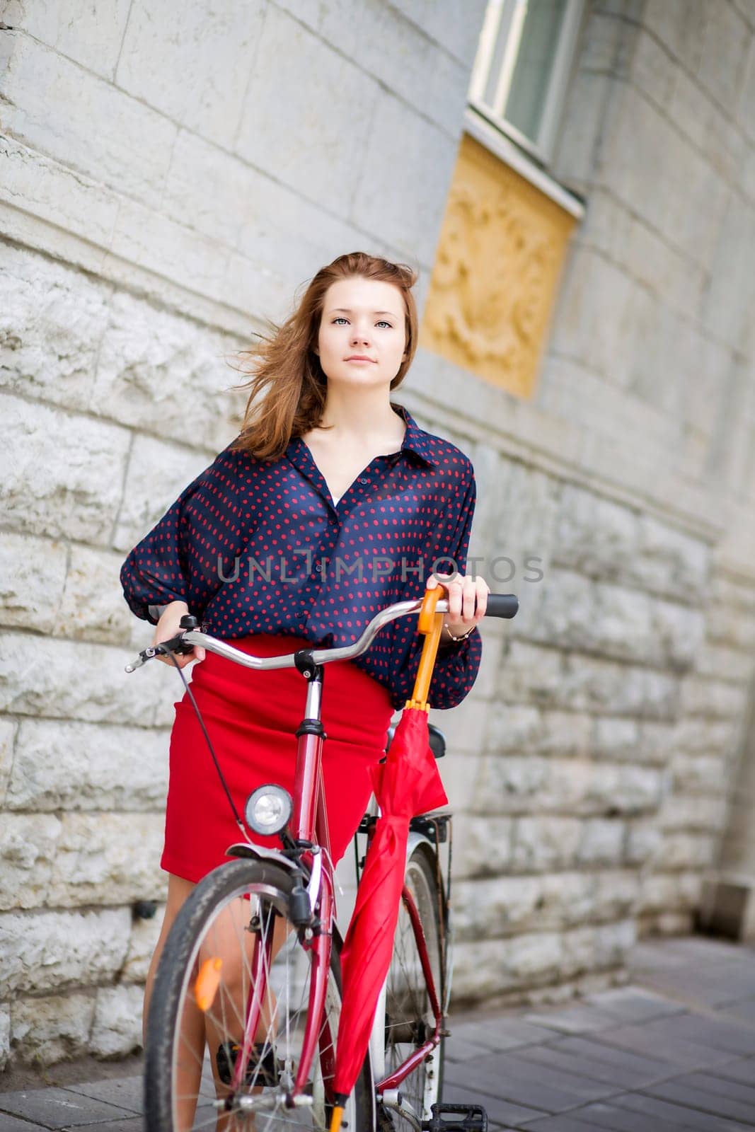 Self-confident woman in red skirt next to bicycle