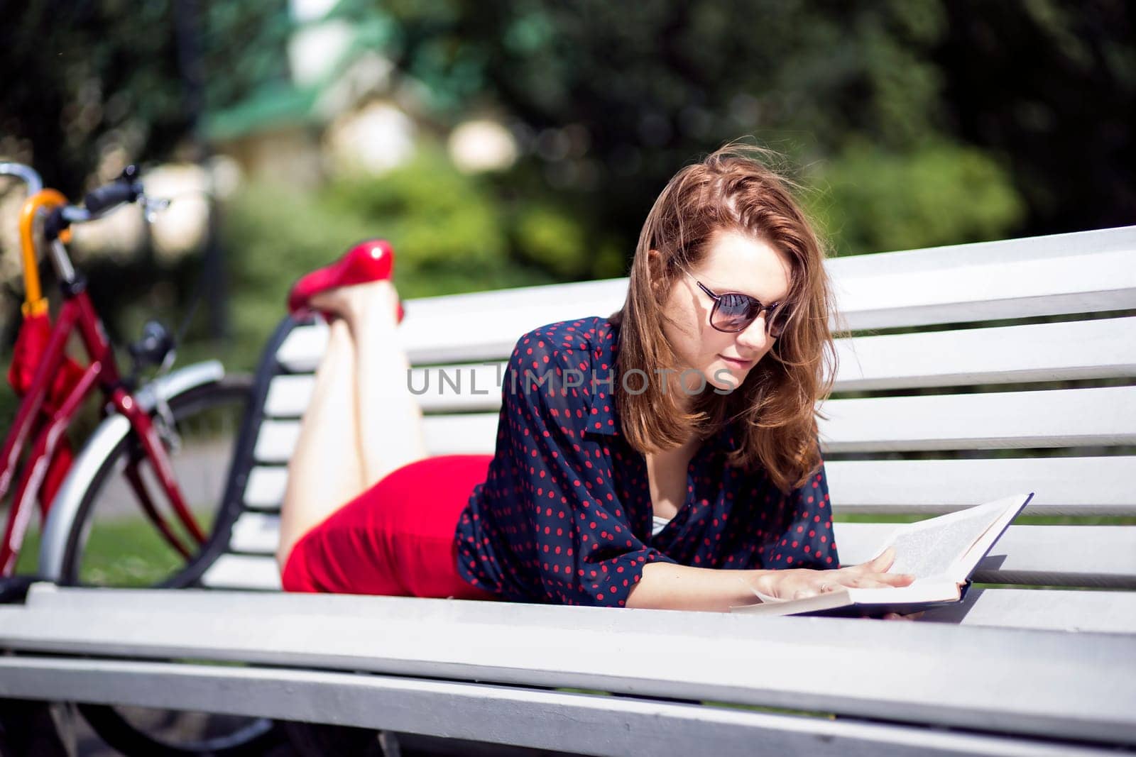 Young woman lying on bench and read book