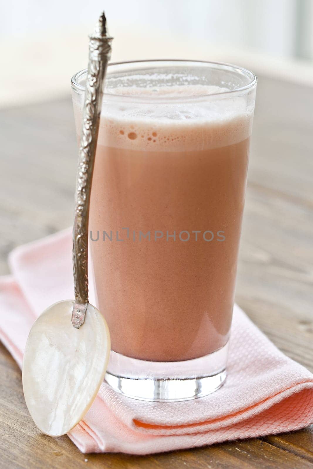 Hot chocolate in narrow glass with old-fashioned loeffel