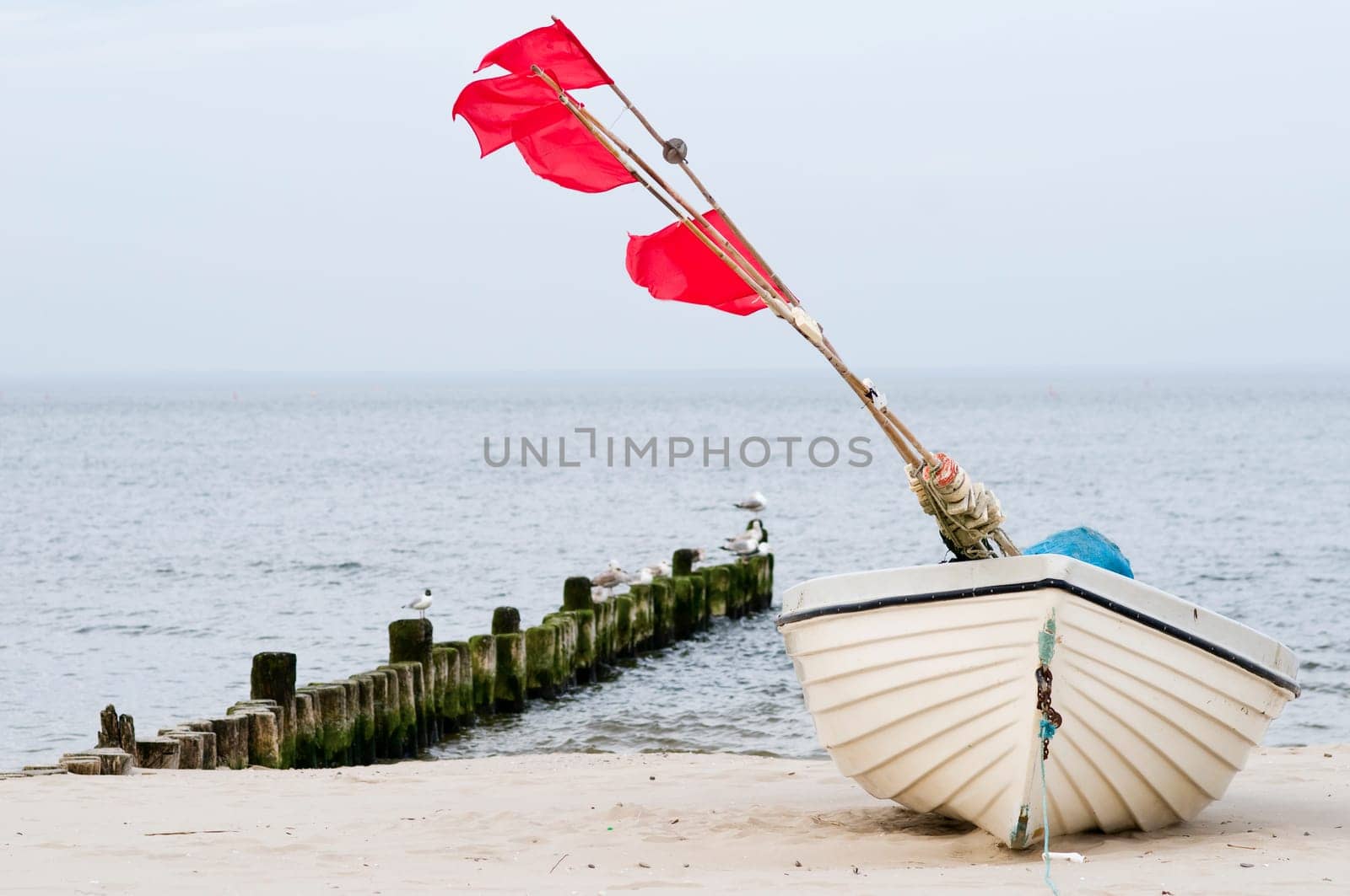 small white fishing boat with red flagged buoys on the Baltic Sea beach near the town of Heringsdorf in summer 2013
