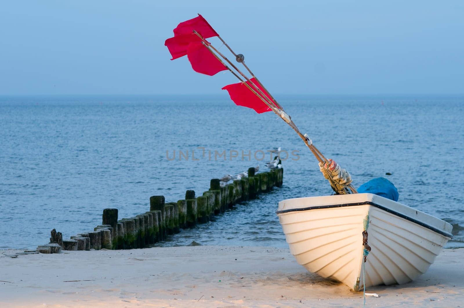 small white fishing boat with red flagged buoys on the Baltic Sea beach near the town of Heringsdorf in summer 2013