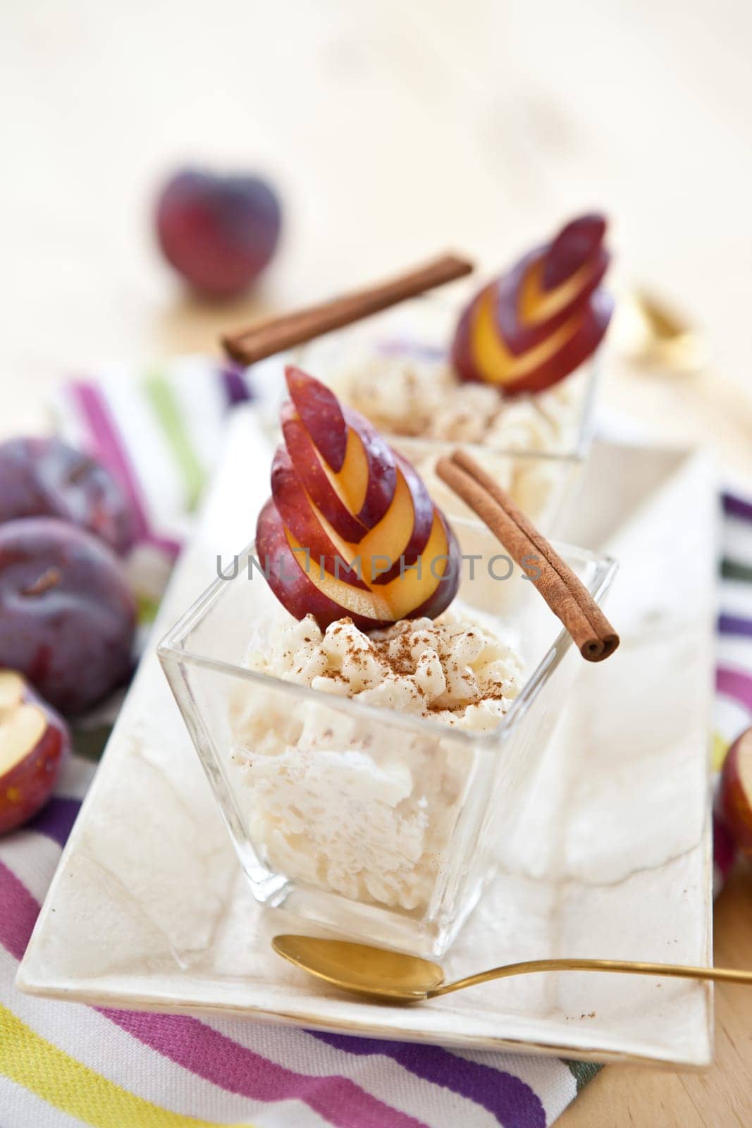 rice pudding in two small bowls with cinnamon and plums