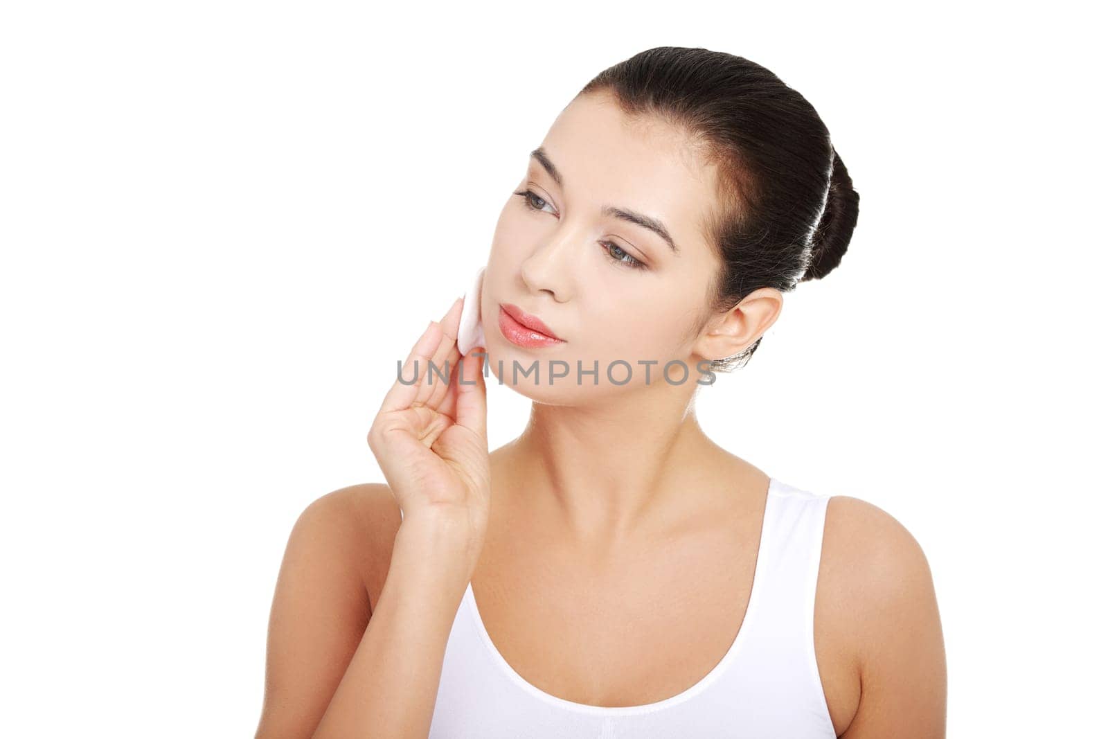 Portrait of happy young woman cleaning skin by cotton pad, over white background