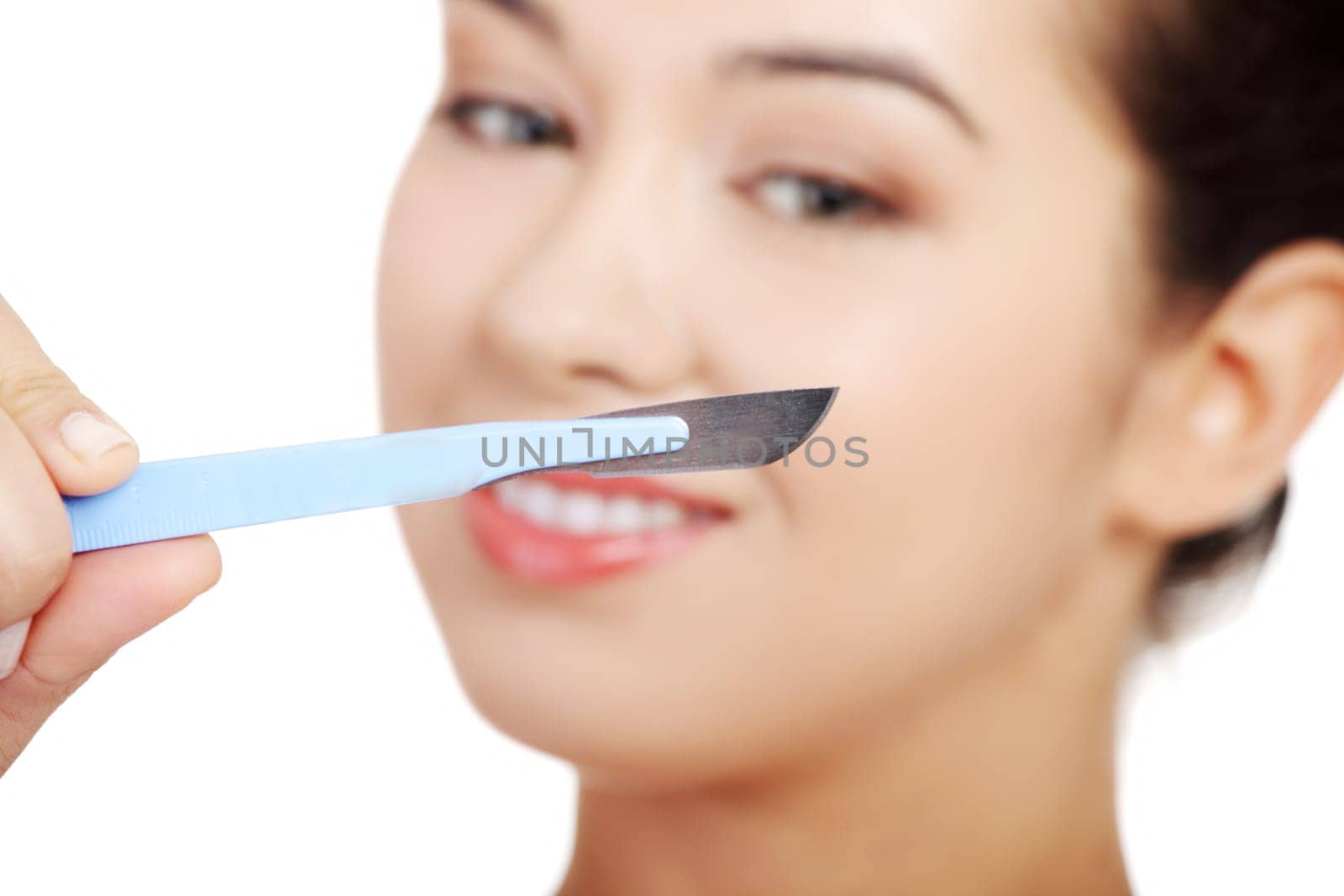 Cosmetic surgery concept. Female face in background of scalpel.