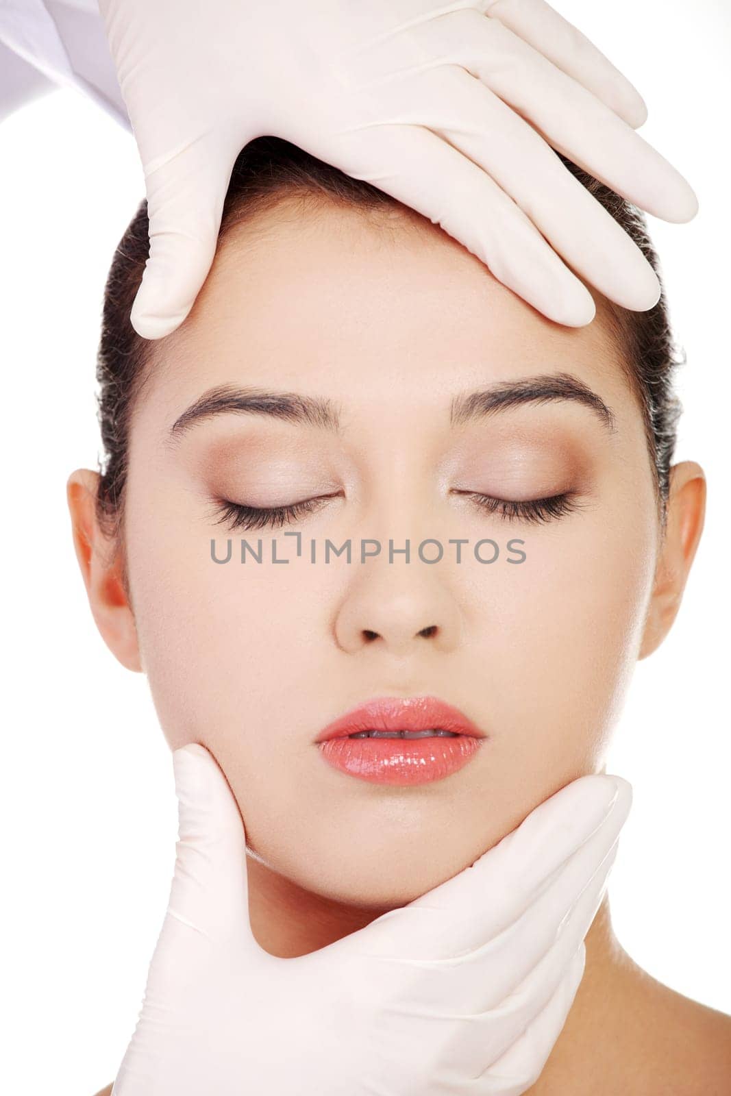 Plastic surgery concept. Doctor hands in gloves touching the beautiful woman face. Isolated on white
