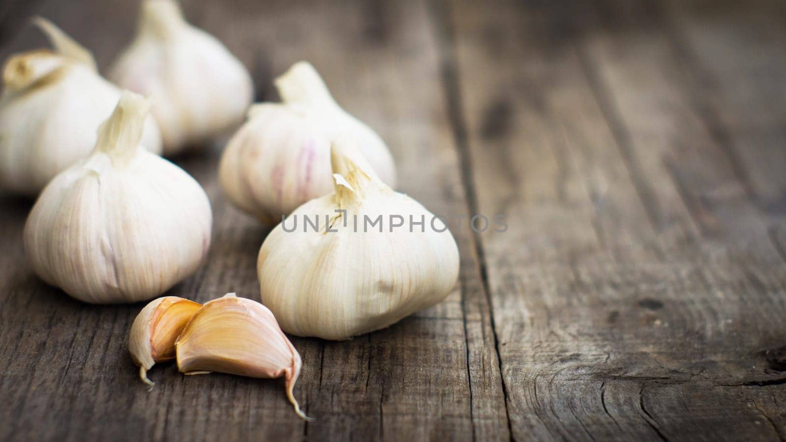 Several fresh garlic cloves on wood background.