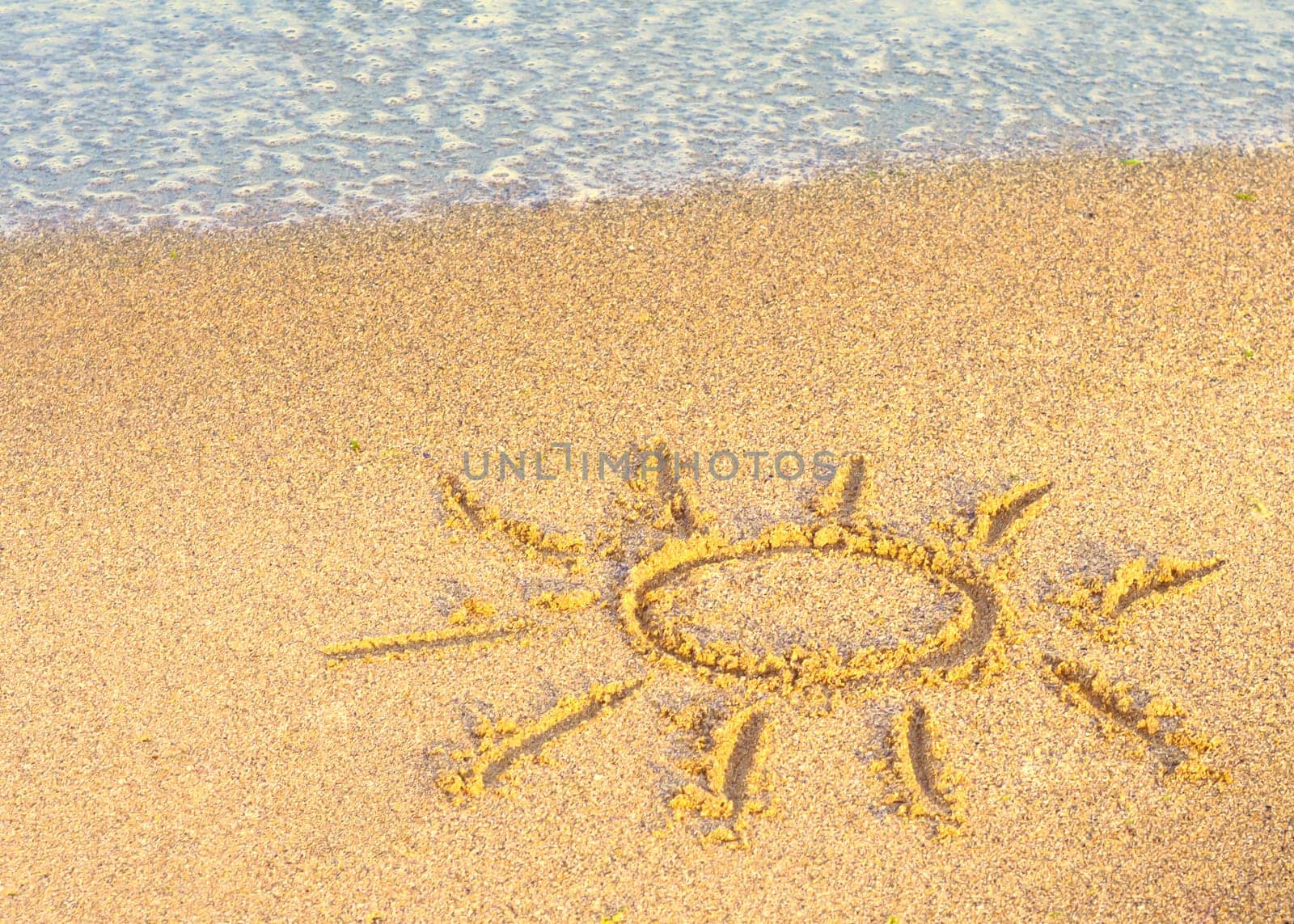 Drawing of the sun on sand with sea wave