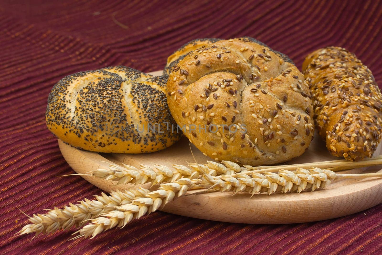 Various types of whole wheat bread and wheat ears lying on a wooden board.