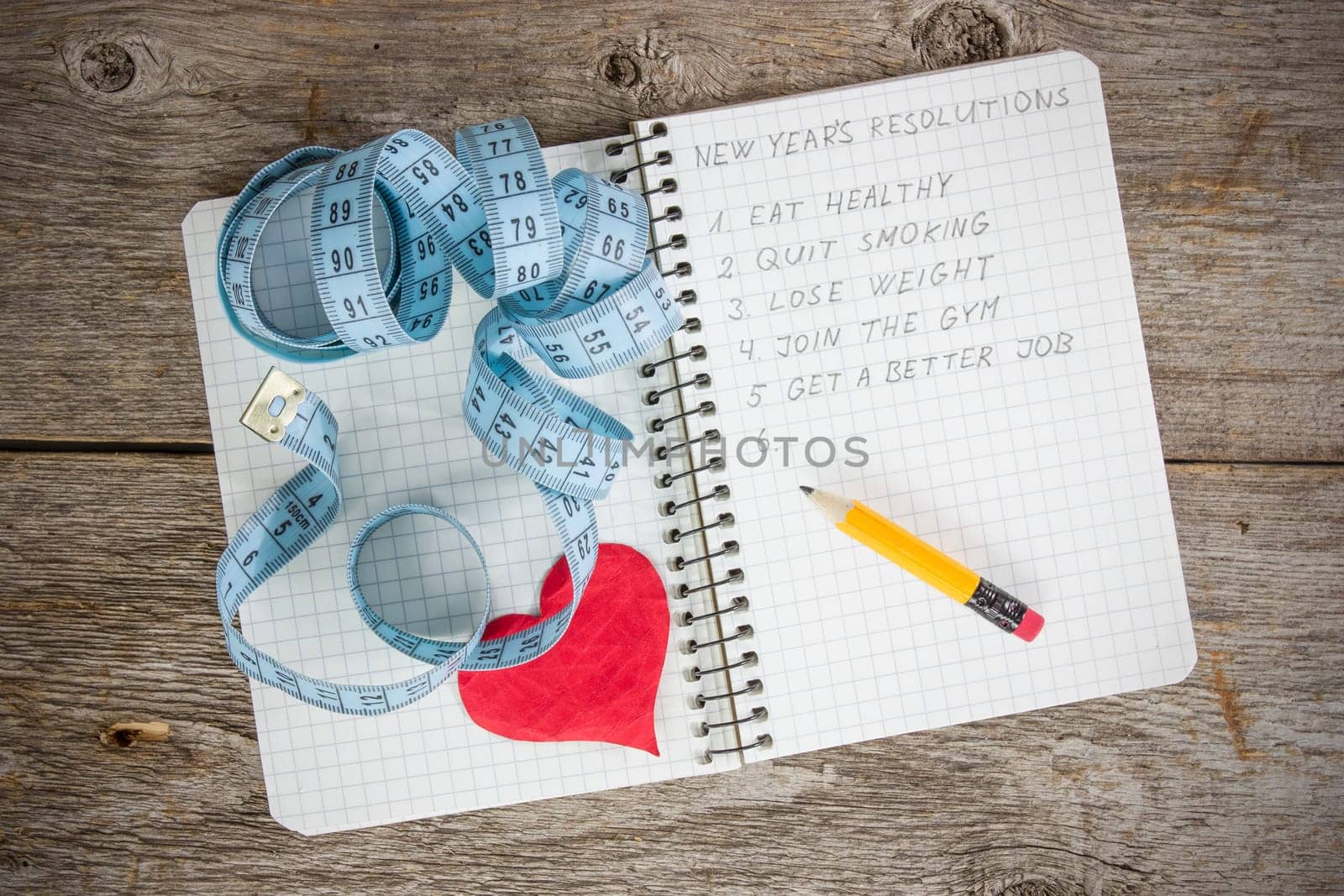 New year's resolutions written on a notepad with a measure tape and heart