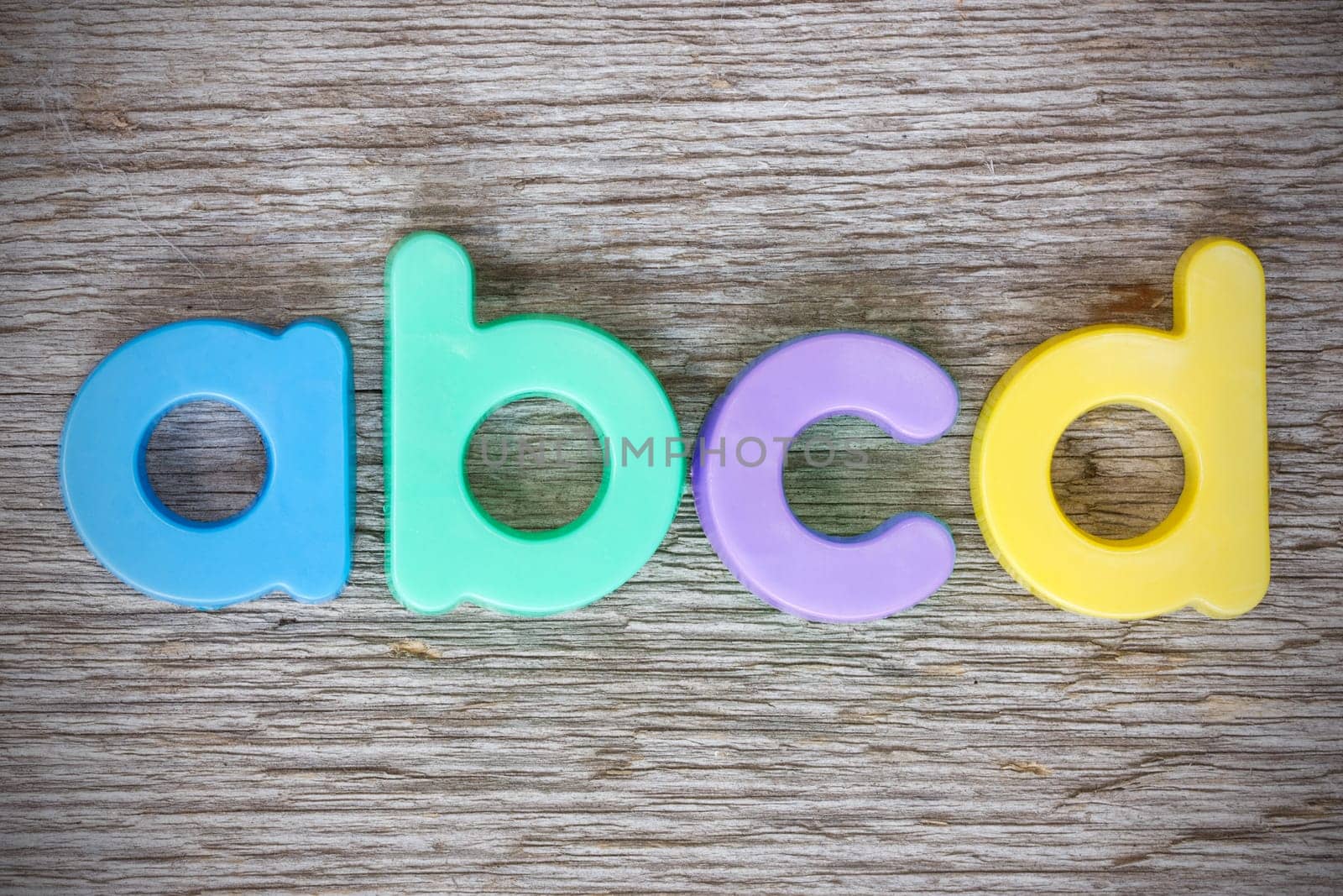 Letter magnets "ABCD"" close up on wood background"