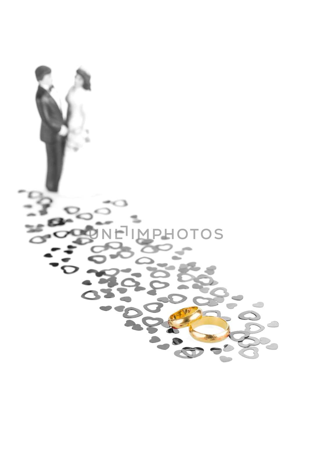 Pure gold wedding rings with hearts ornament and wedding couple at the background