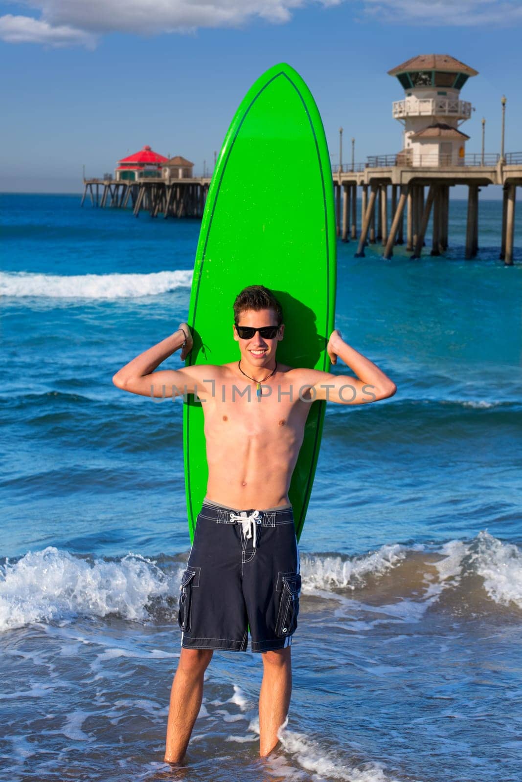 Boy teen surfer holding surfboard in Huntinton Beach pier California