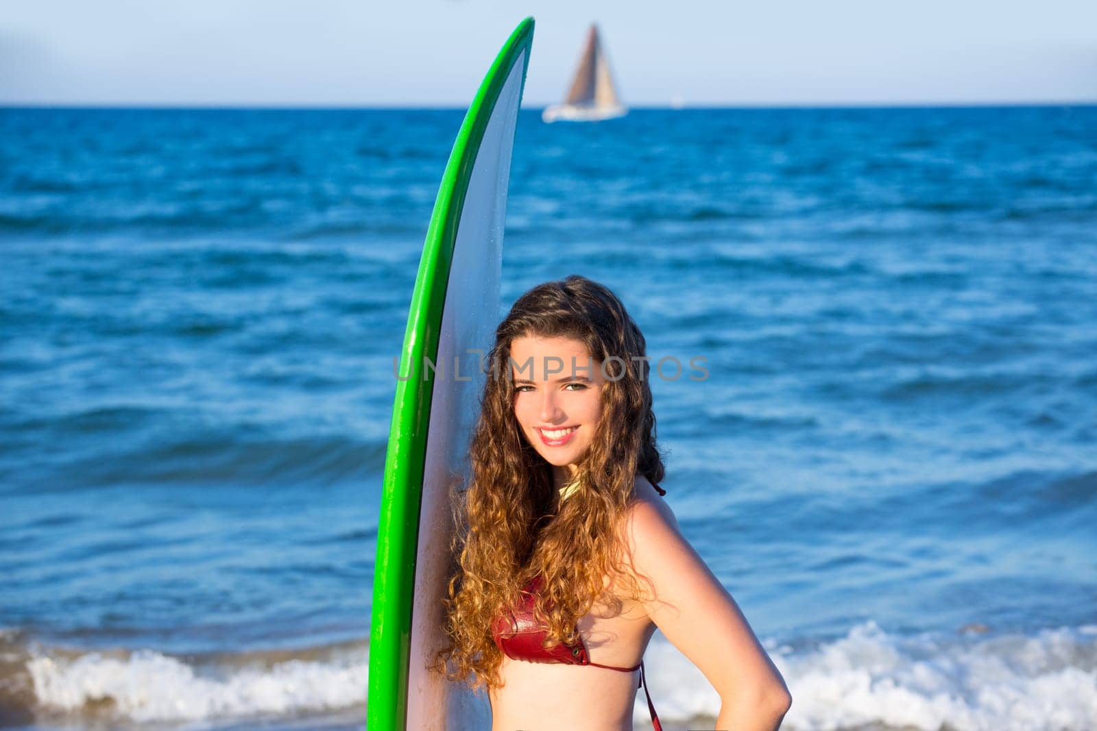 Young surfer girl holding surfboard in blue beach
