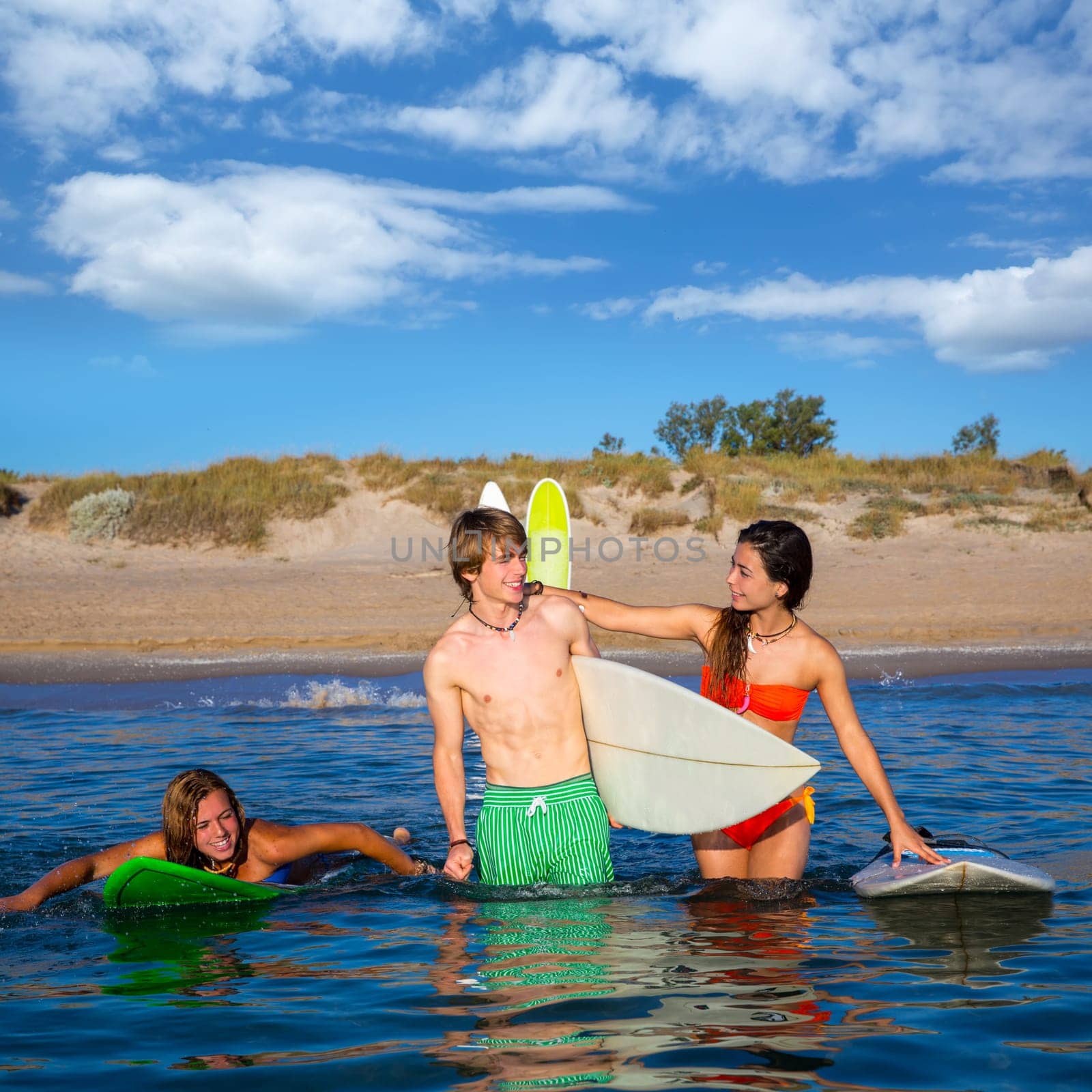 Happy beautiful teen surfers talking on beach shore smiling