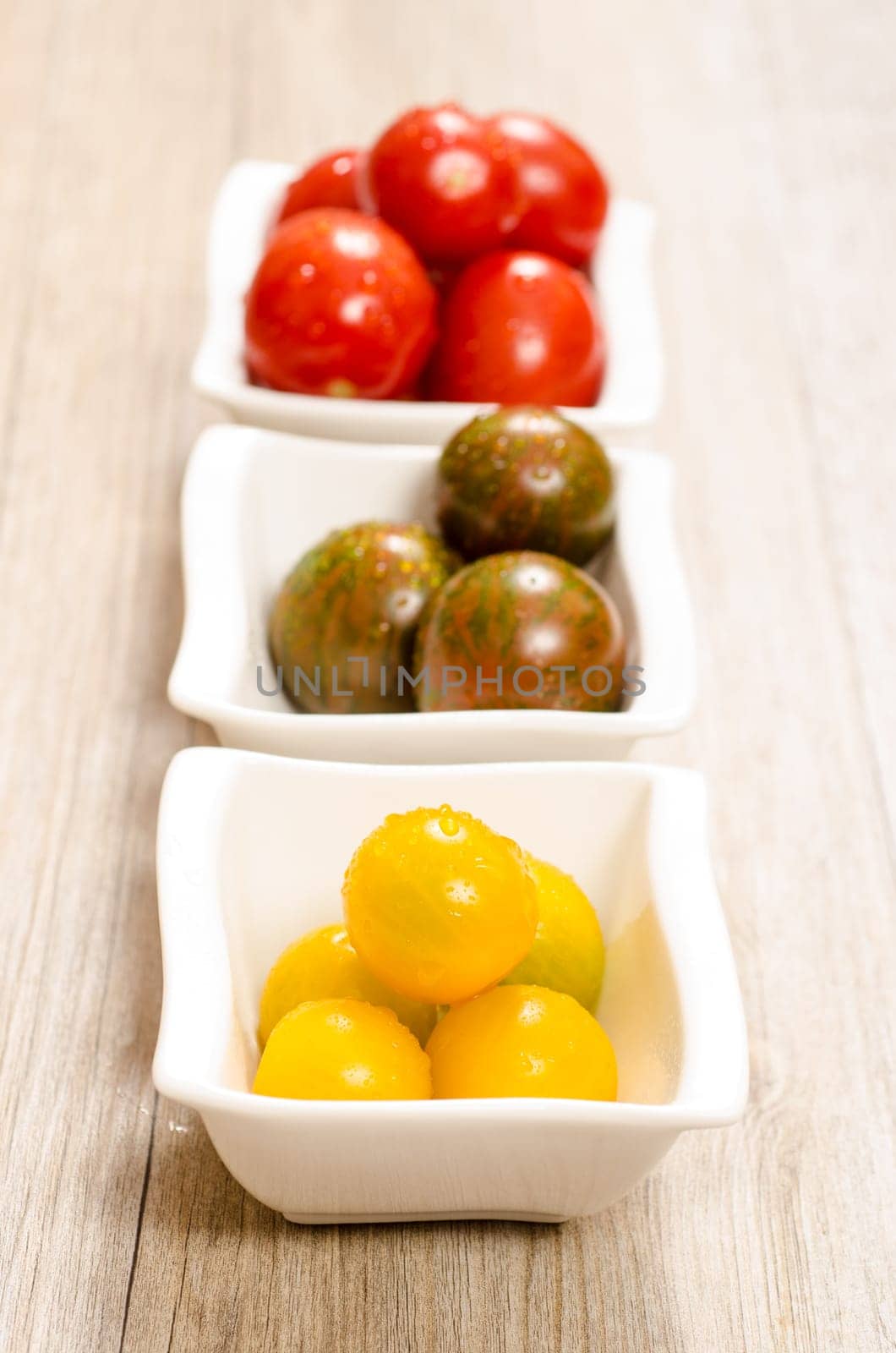 Yellow tomatoes in three bowls in portrait format