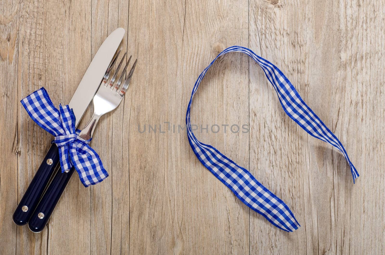 Knife and gable and blue checkered fabric ribbon on a dining table