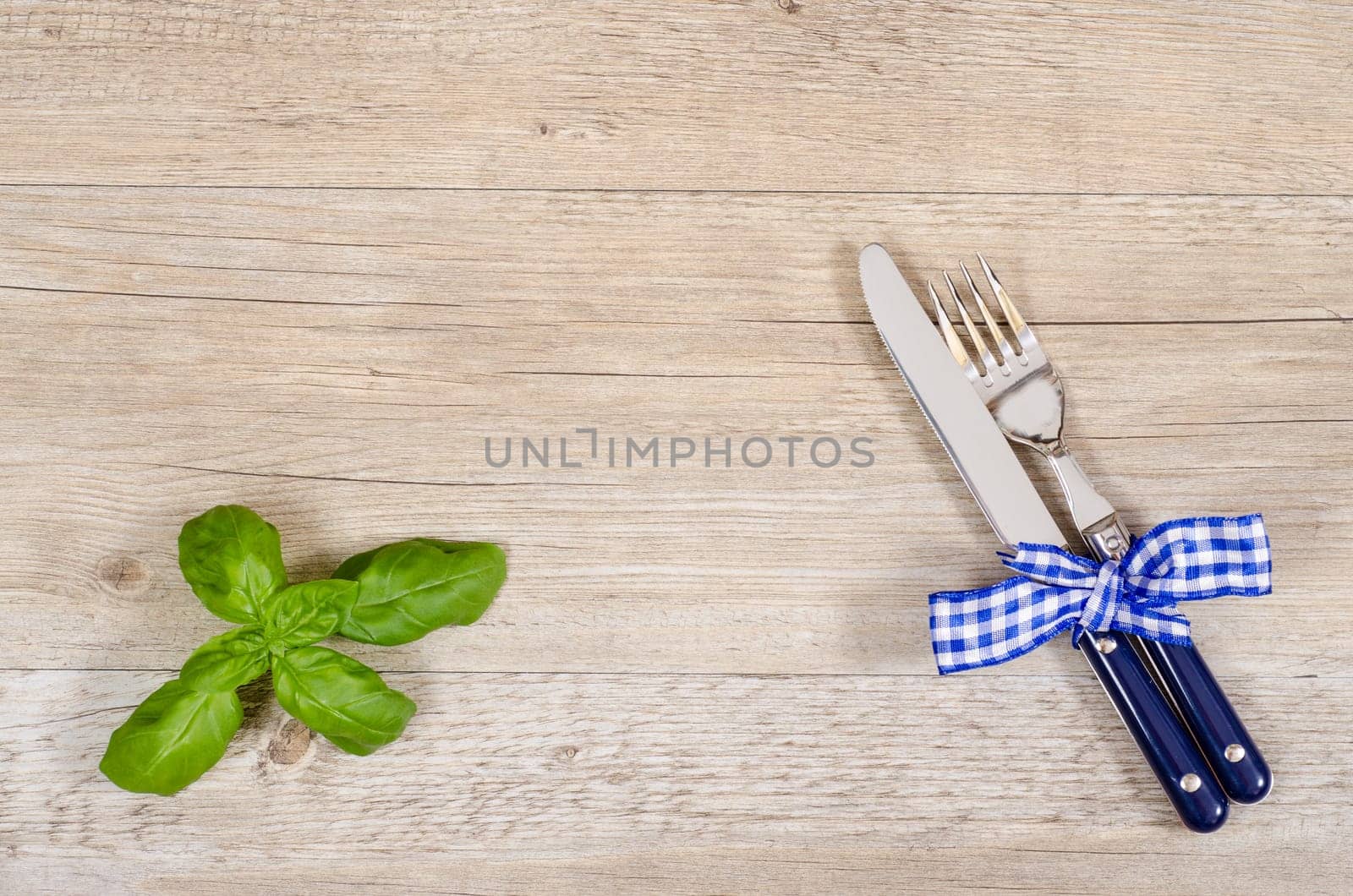 Knife and fork with checkered fabric bow on dining table with text space