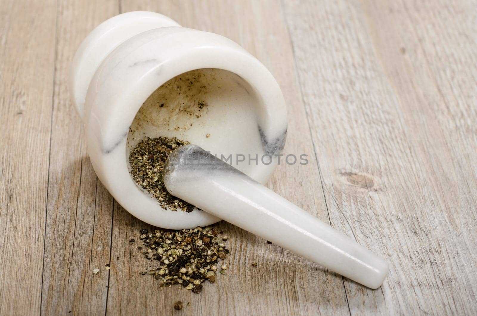 Crushed black pepper in mortar with marble pestle