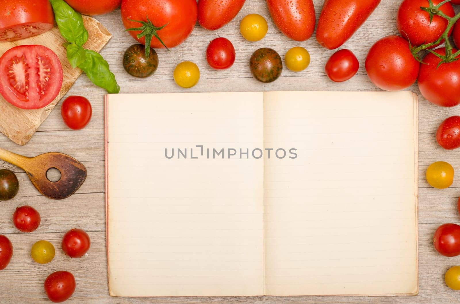 Frame of wet tomatoes with cooking spoon and text space in a cookbook