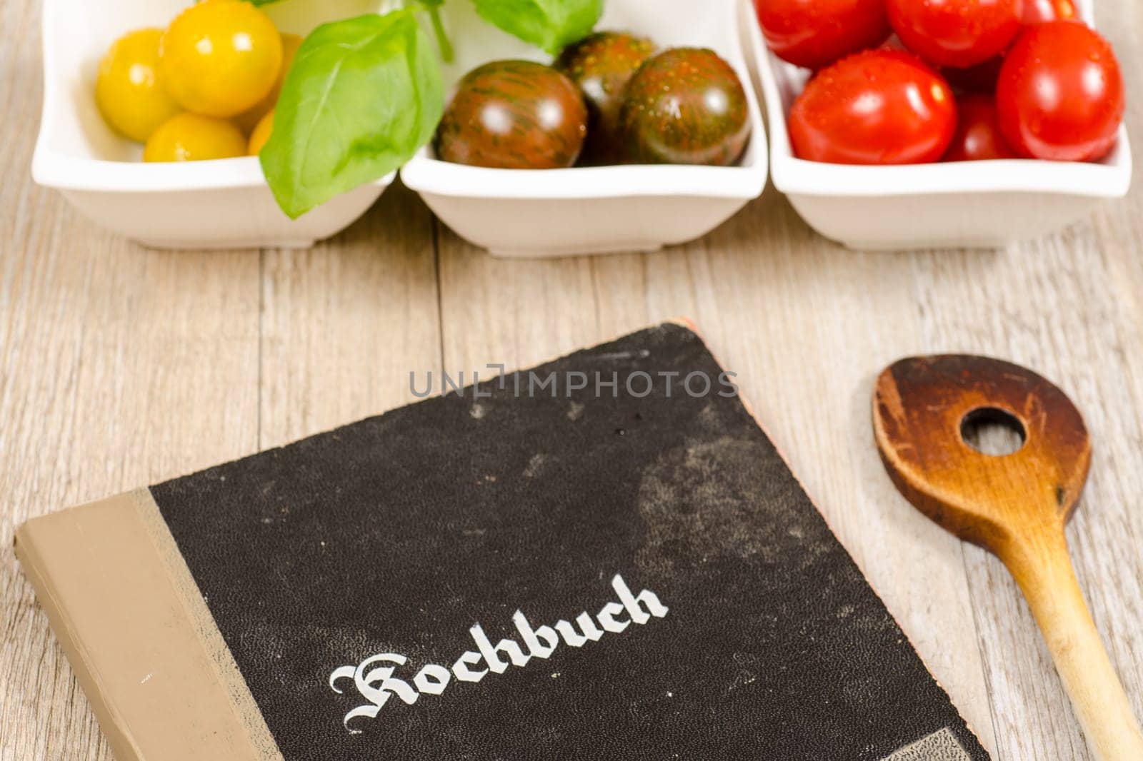 Vintage cookbook with cooking spoon and tomatoes as an ingredient for recipe