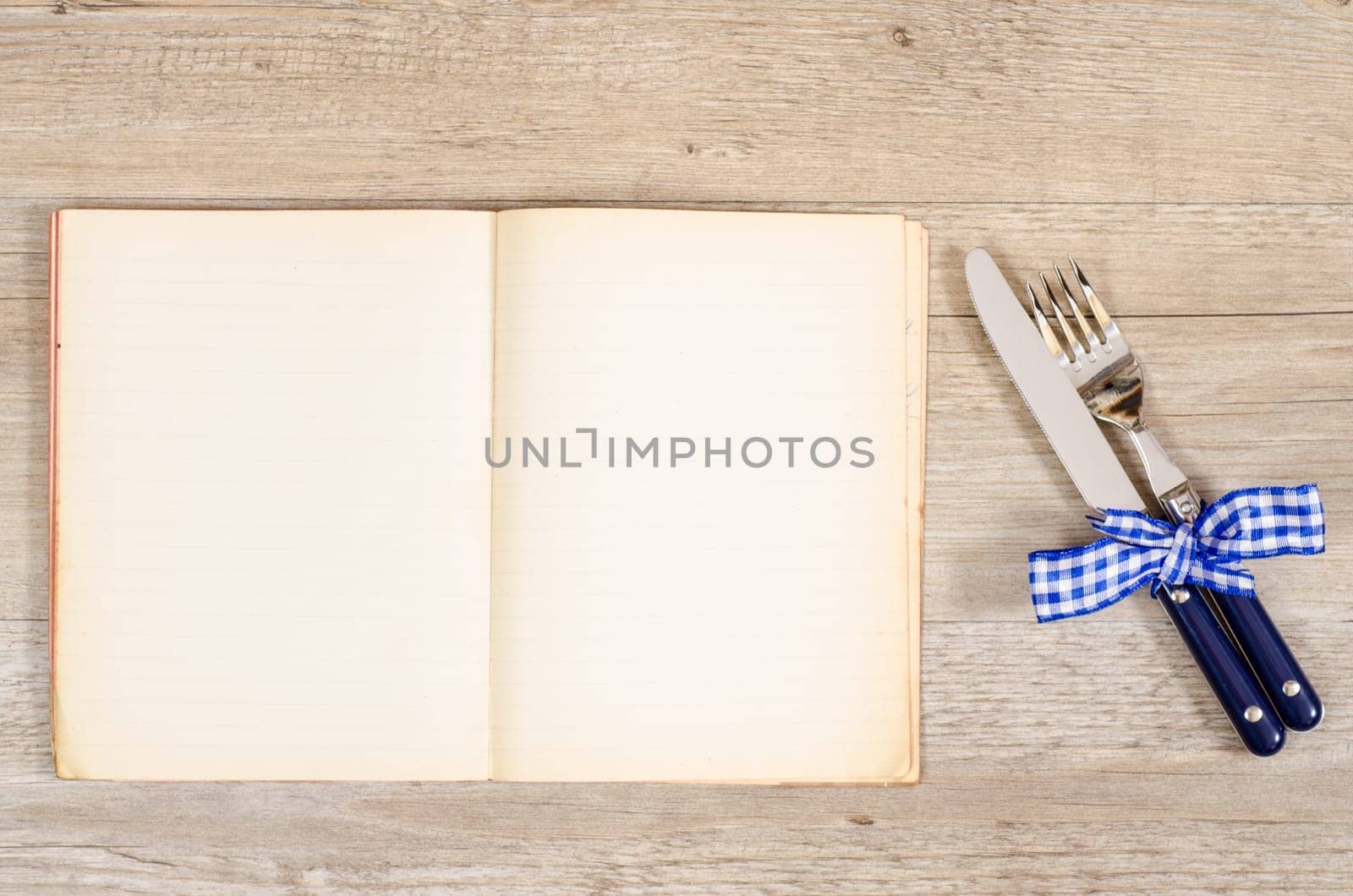 Knife and gable with blue bow and an old book with text space
