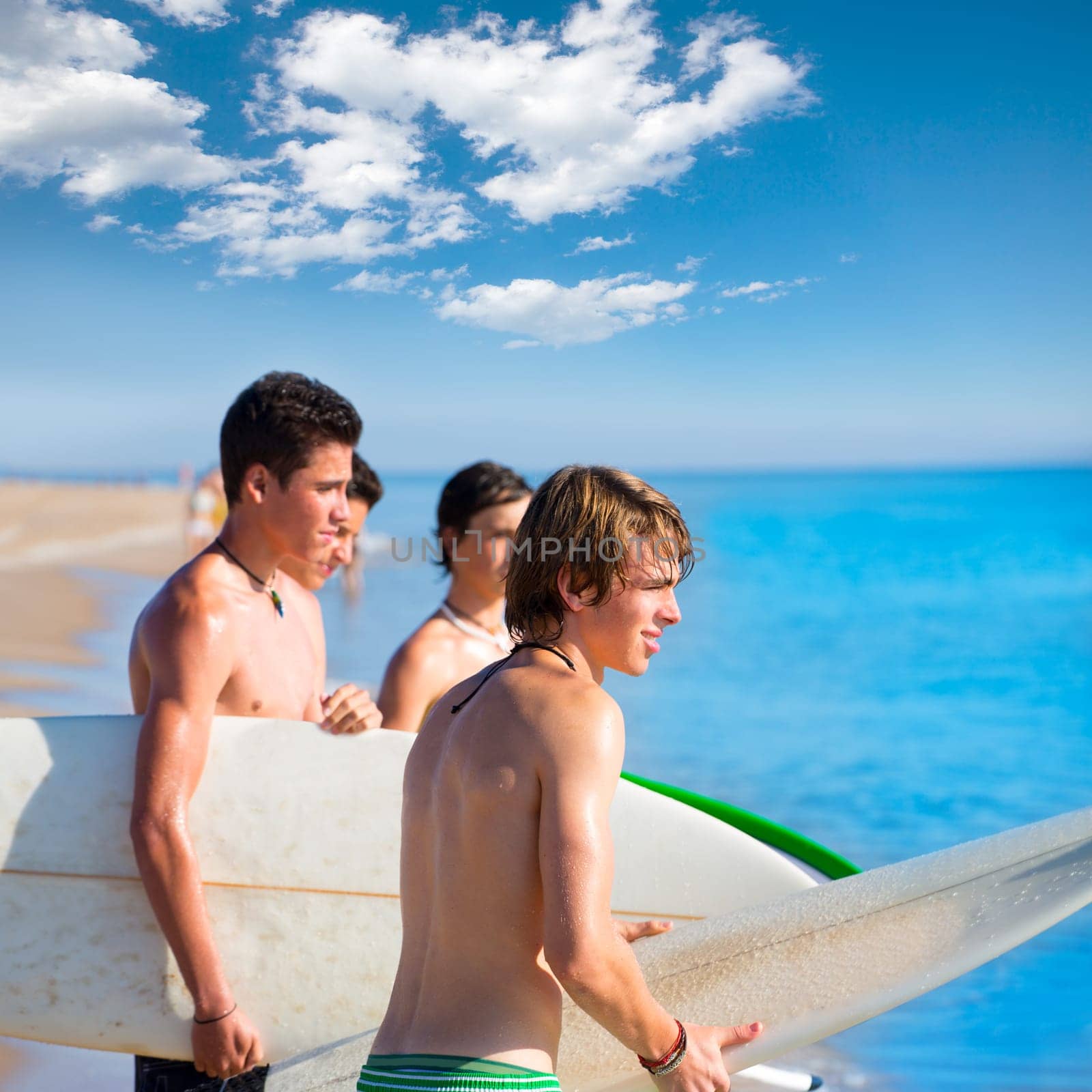 Surfer teen boys talking on beach shore holding surfboards