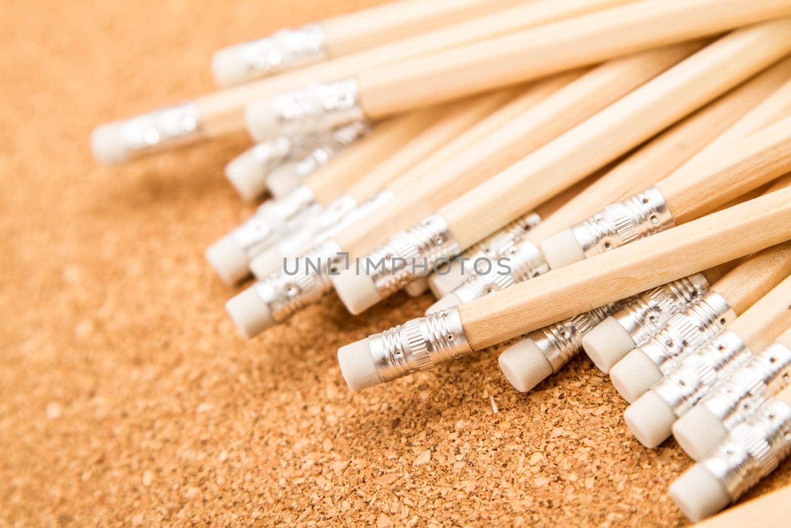 Bunch of wooden pencils over a cork board.