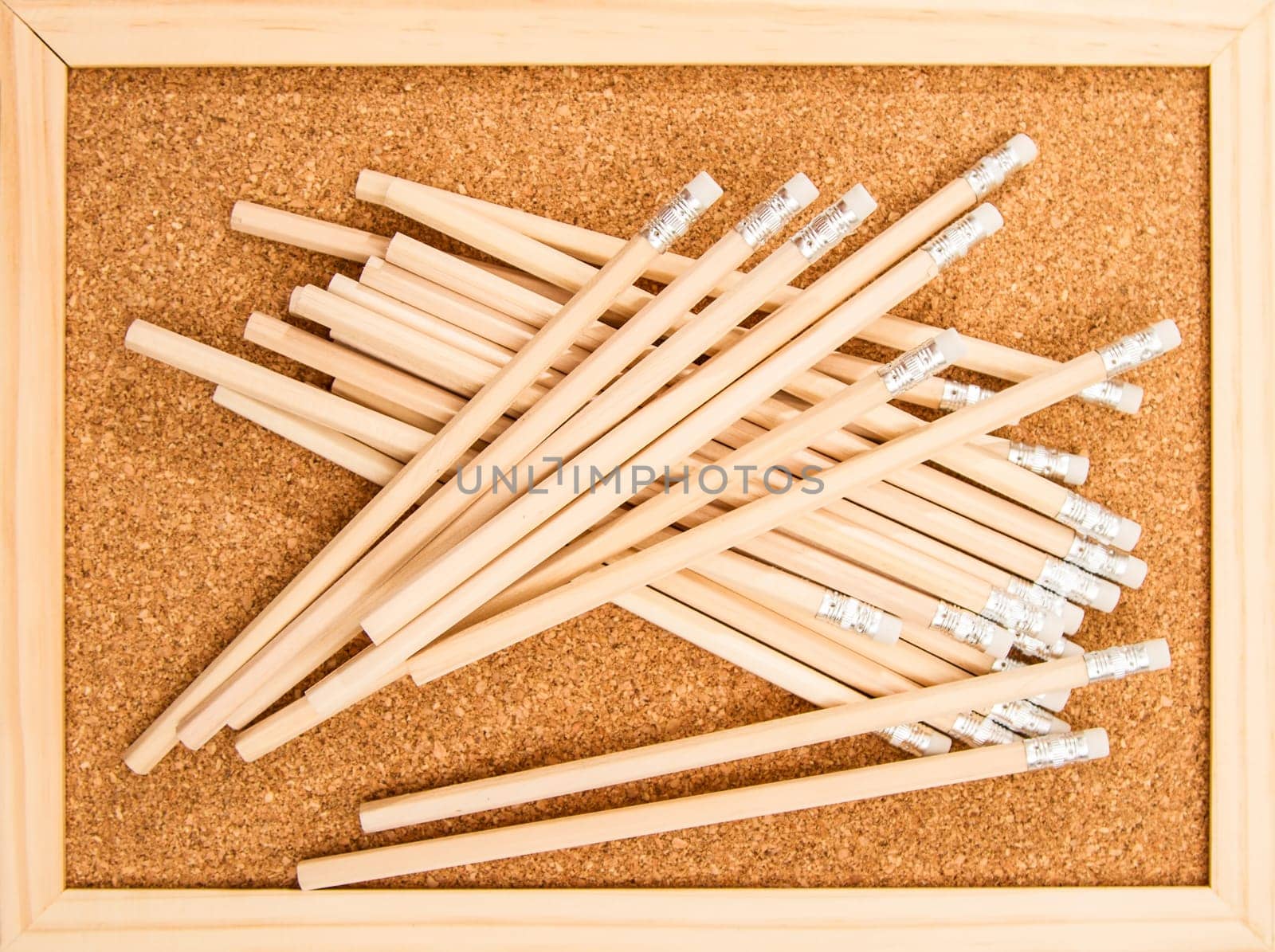 Bunch of wooden pencils over a cork board.