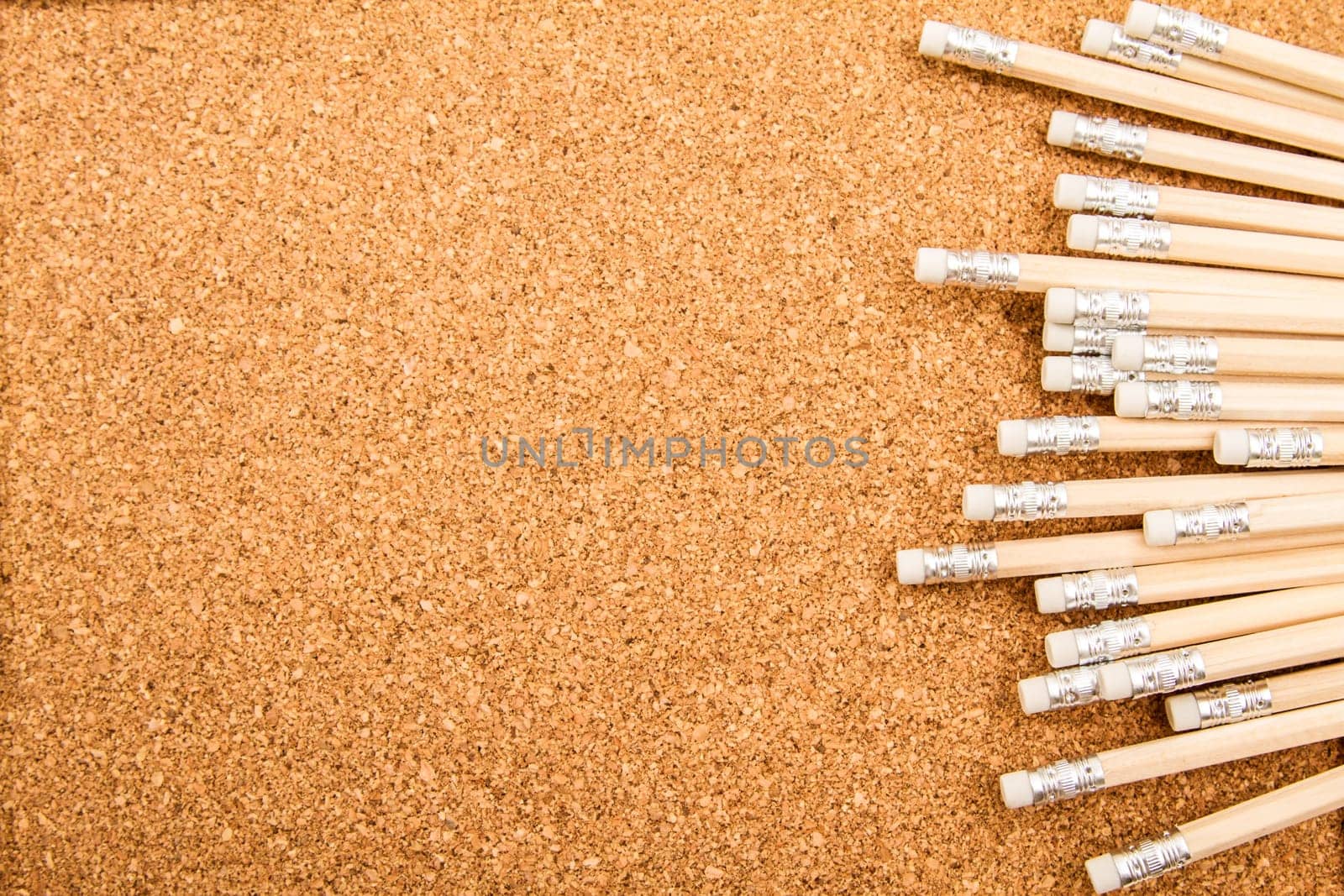 Bunch of wooden pencils over a cork board.