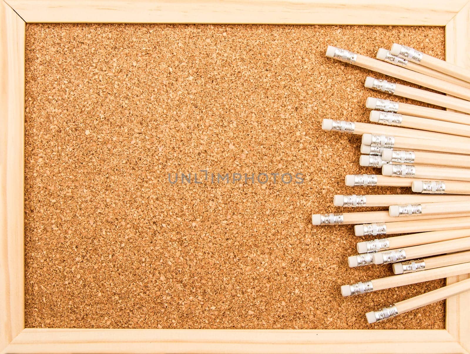 Bunch of wooden pencils over a cork board.