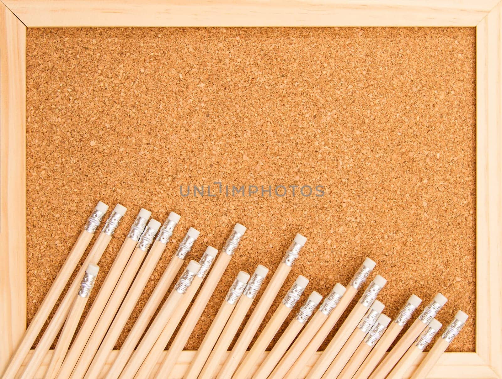 Bunch of wooden pencils over a cork board.